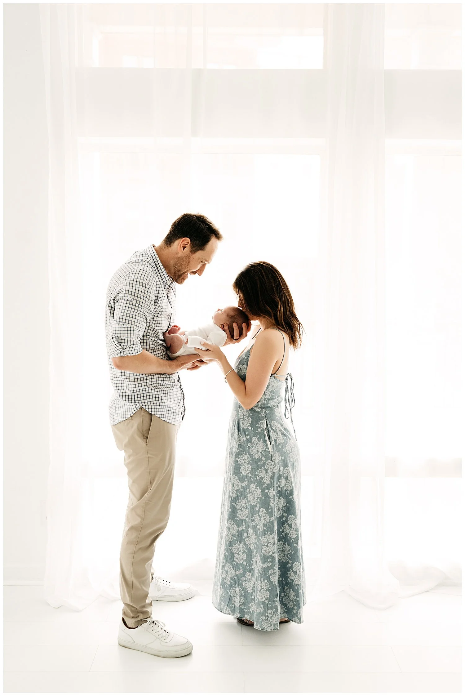 An image depicting a mother and father holding their newborn son, while looking at him lovingly.