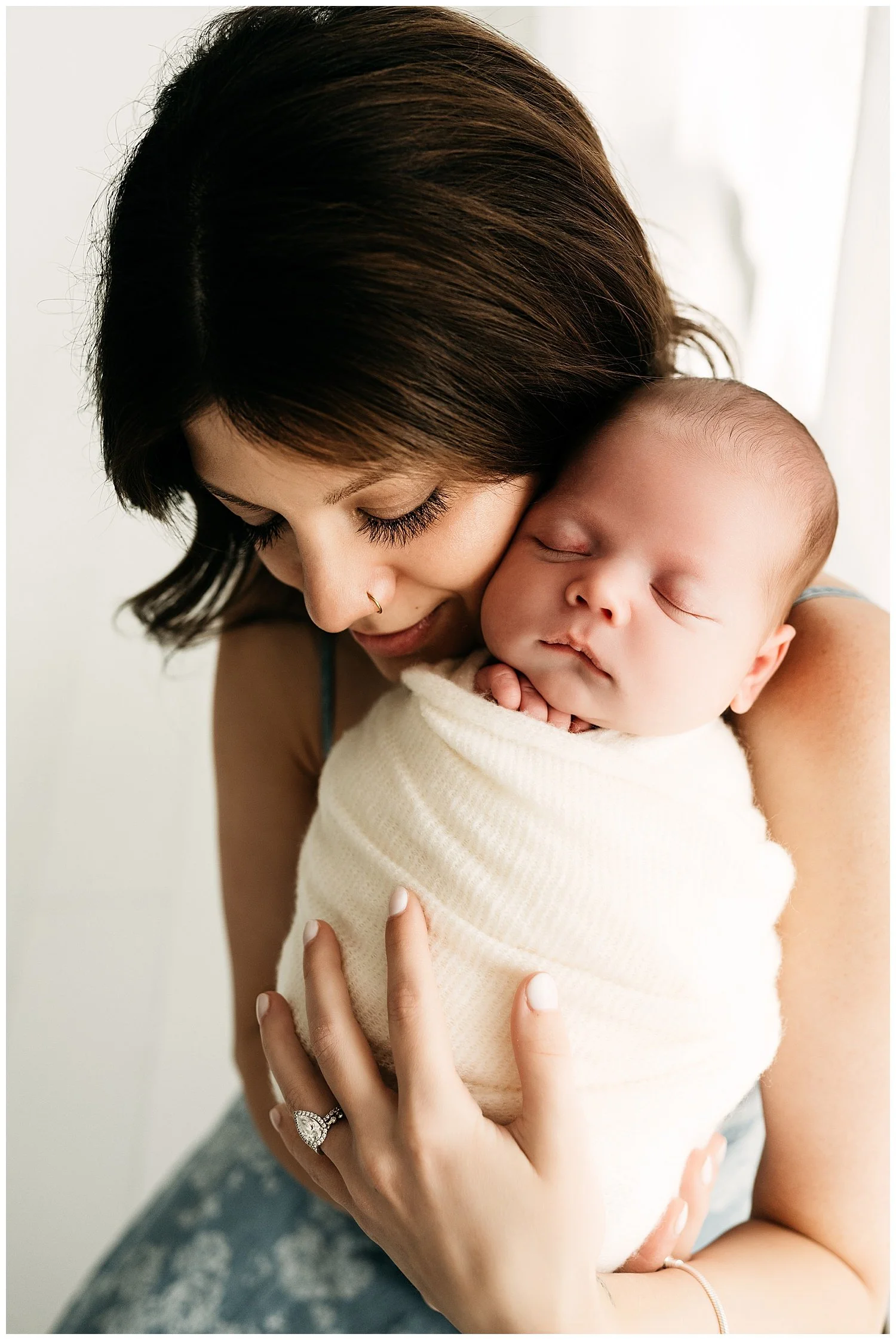 An image depicting a mother holding her newborn son, while looking at him lovingly.