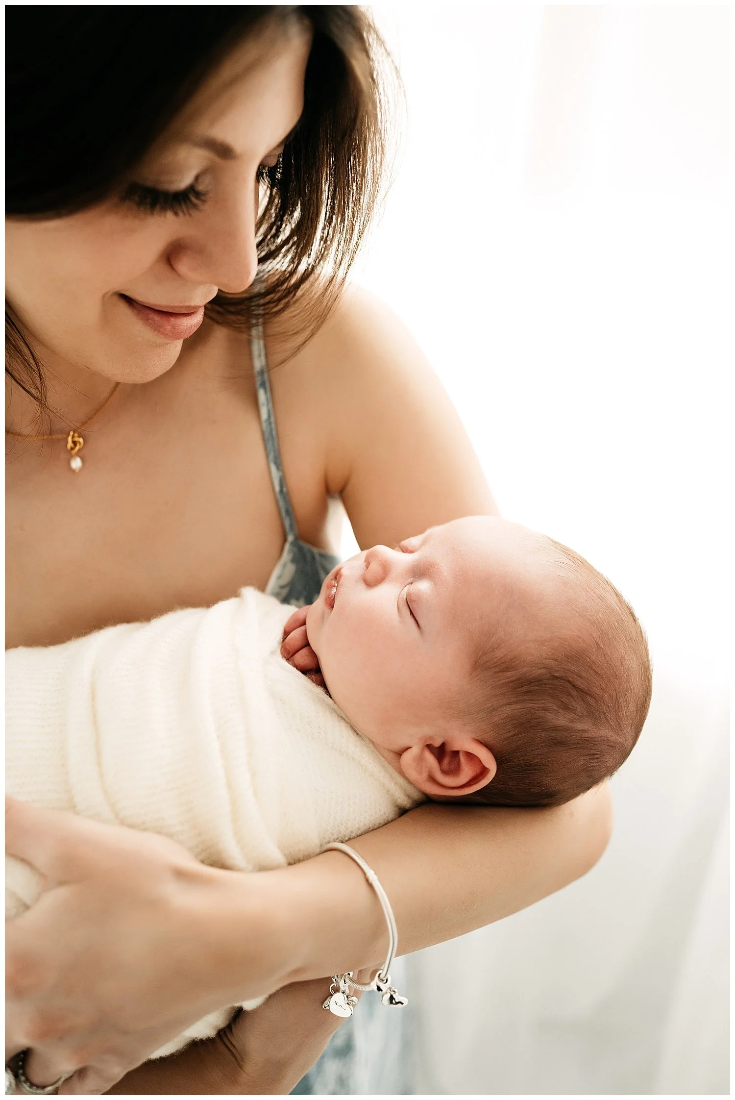 An image of a couple looking lovingly into each other's eyes as they hold their newborn.