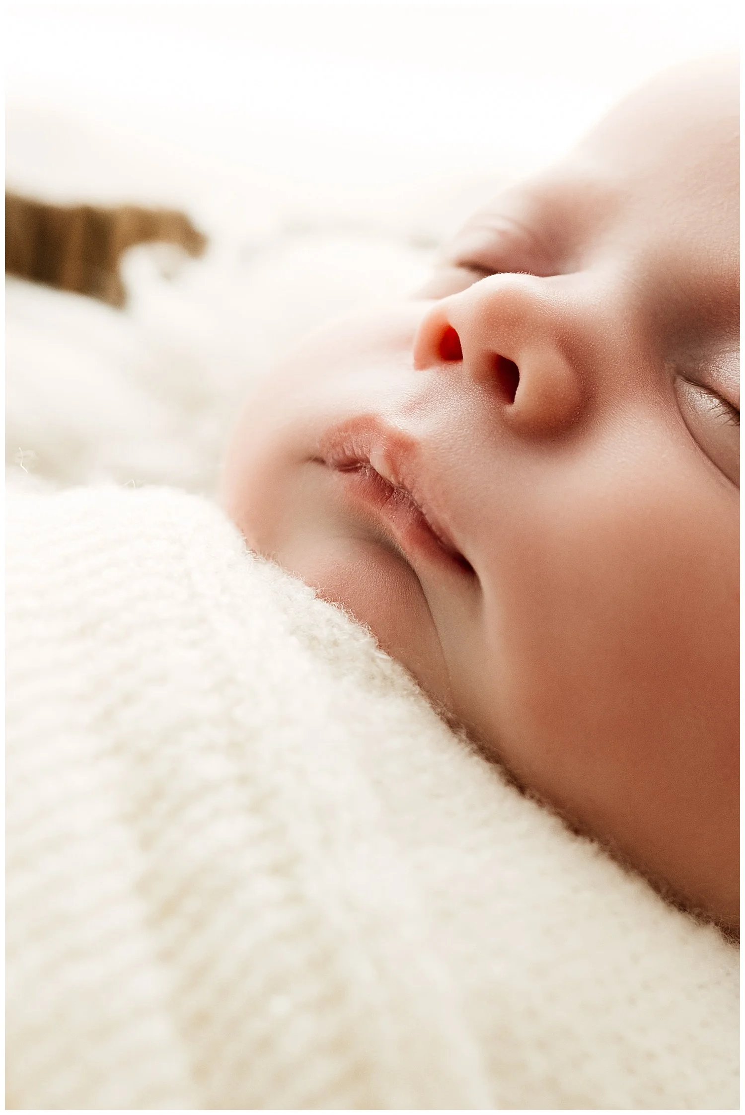 Close-up photo of newborn baby; focus is on his nose and lips as he sleeps peacefully
