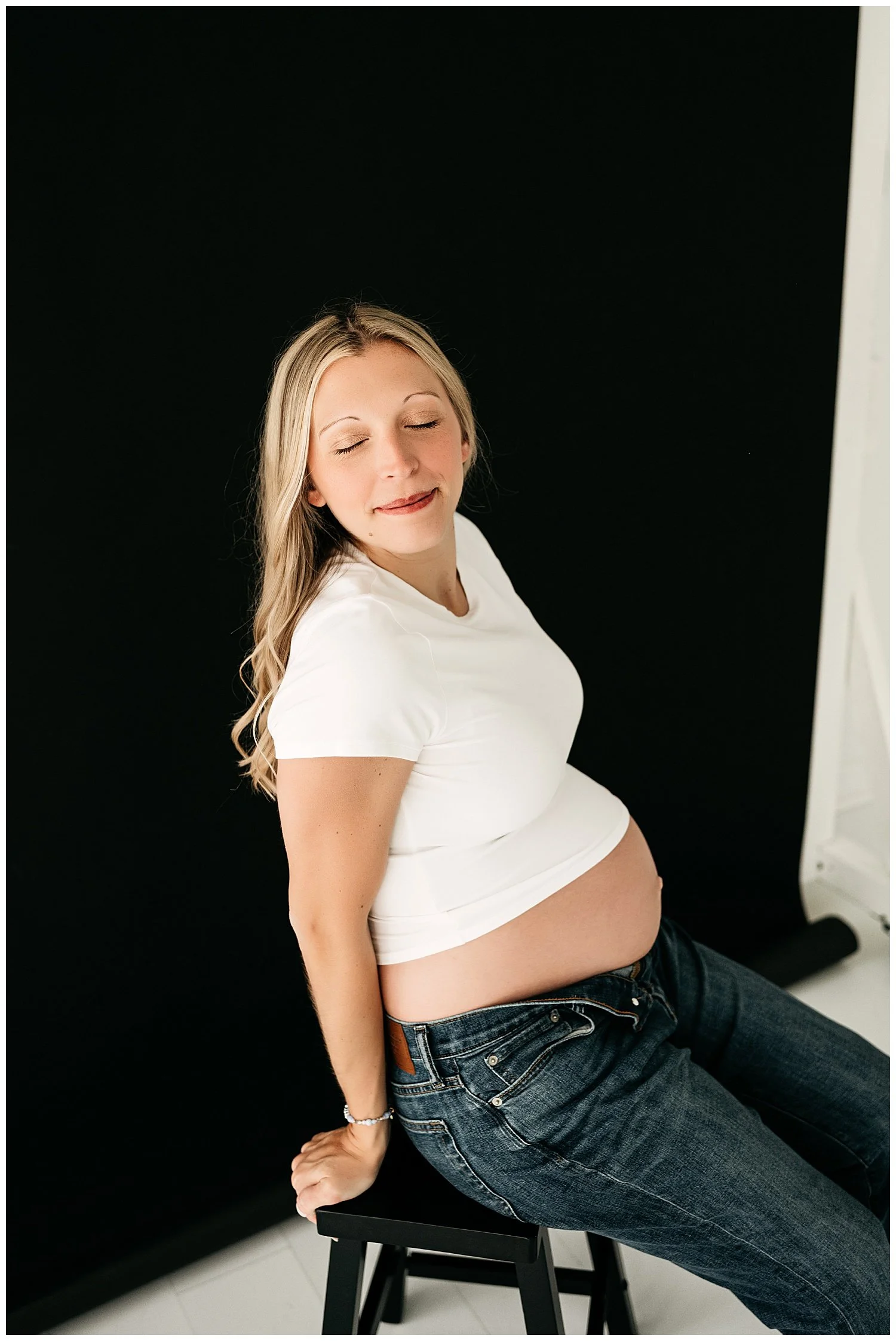 Expectant mother leans back to expose her belly, her expression is relaxed.