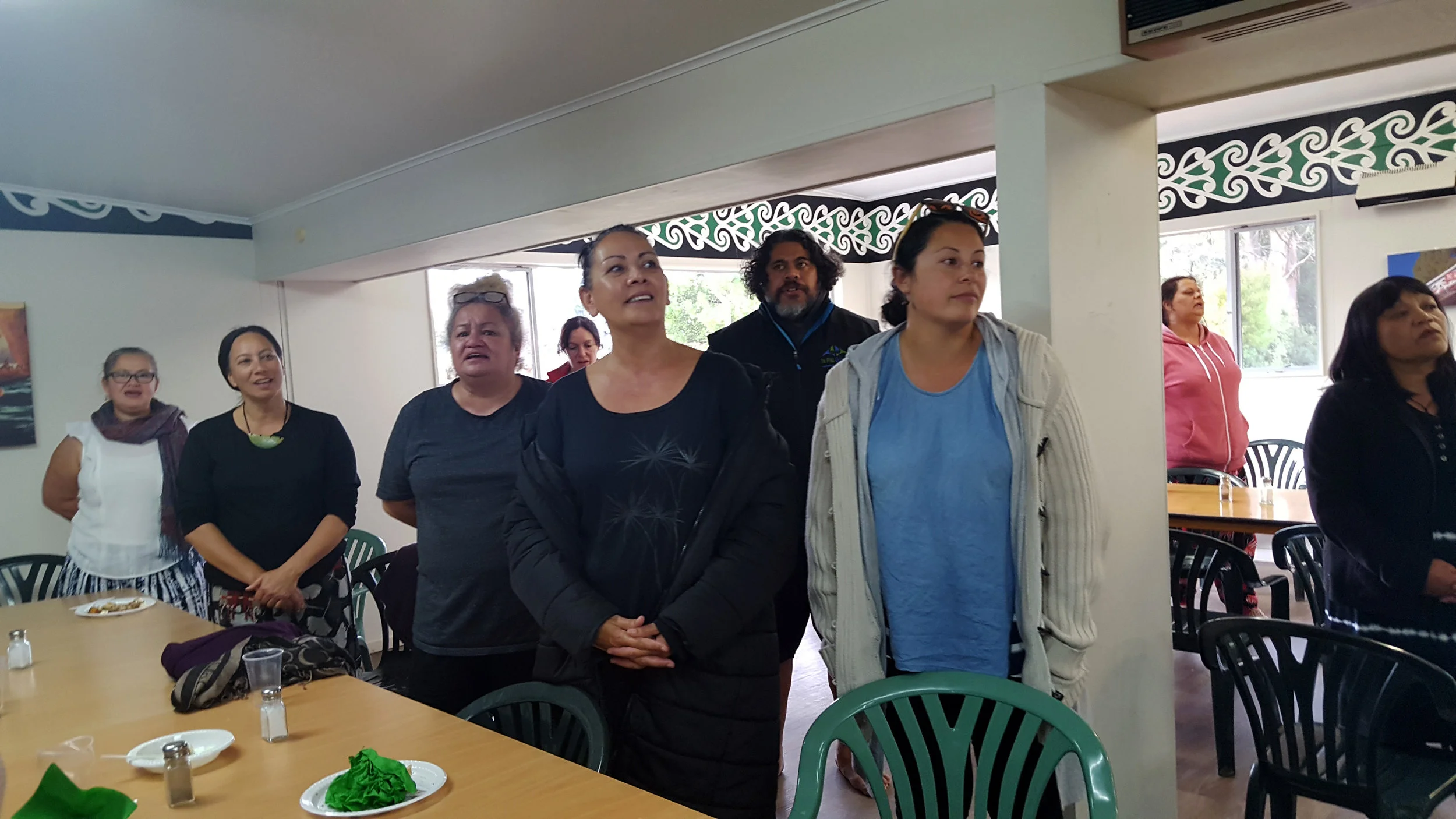 Kaimahi singing "Io, Io" waiata inside the wharekai.