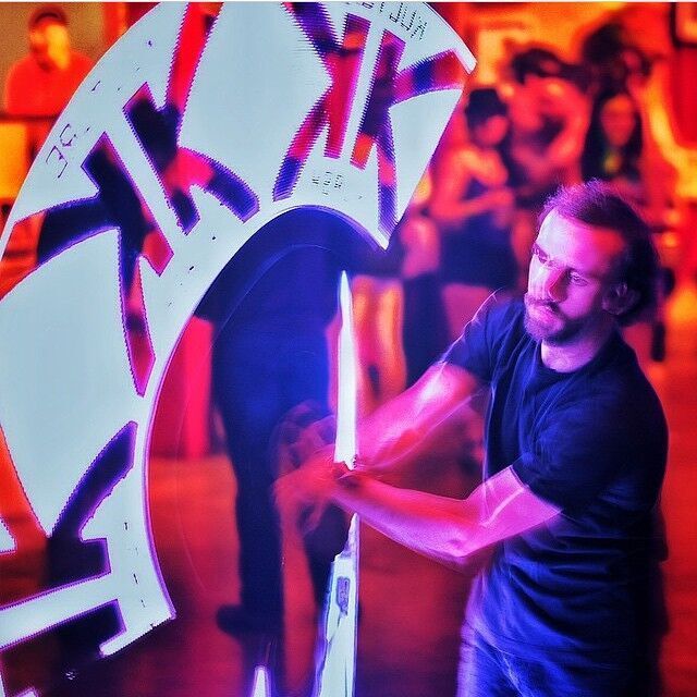 Performer spinning LED Poi creating a design of a corporate logo in the air
