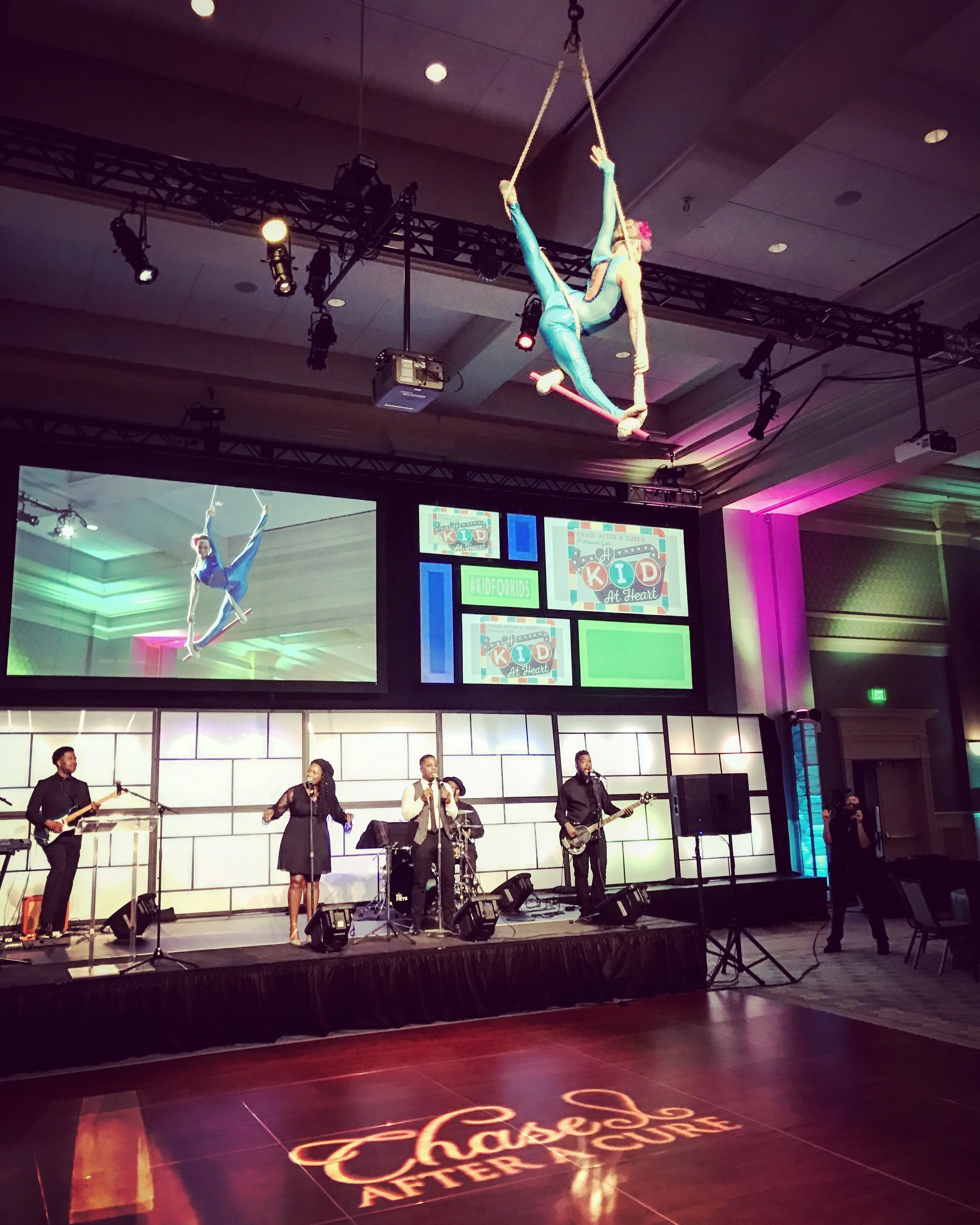 Trapeze Performance in Blue-Green Costume with Live Band