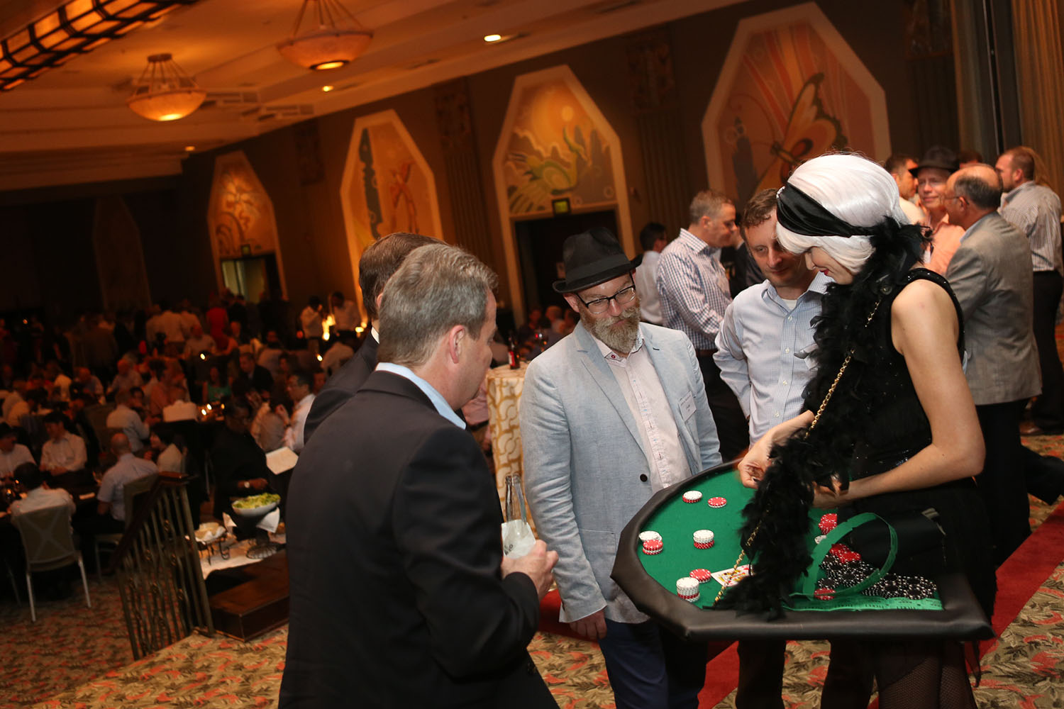 Blackjack Girl in a black costume with black feather boa carrying her blackjack table around her neck for a casino night themed event inside a ballroom