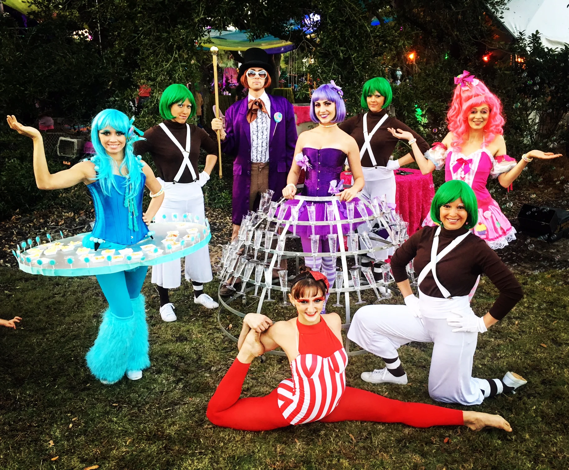 Four performers costumed in either red, pink, purple or blue with a champagne dress, LED table, or contortionist. Four performers costumed as either Oompa Loompas or Willy Wonka inspired characters