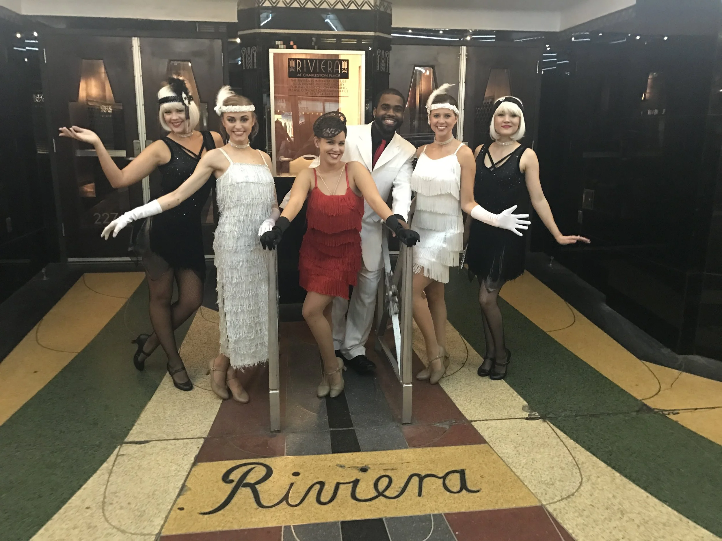 Six performers costumed in black, white, or red flapper costumes for a 1920s event in Charleston, SC