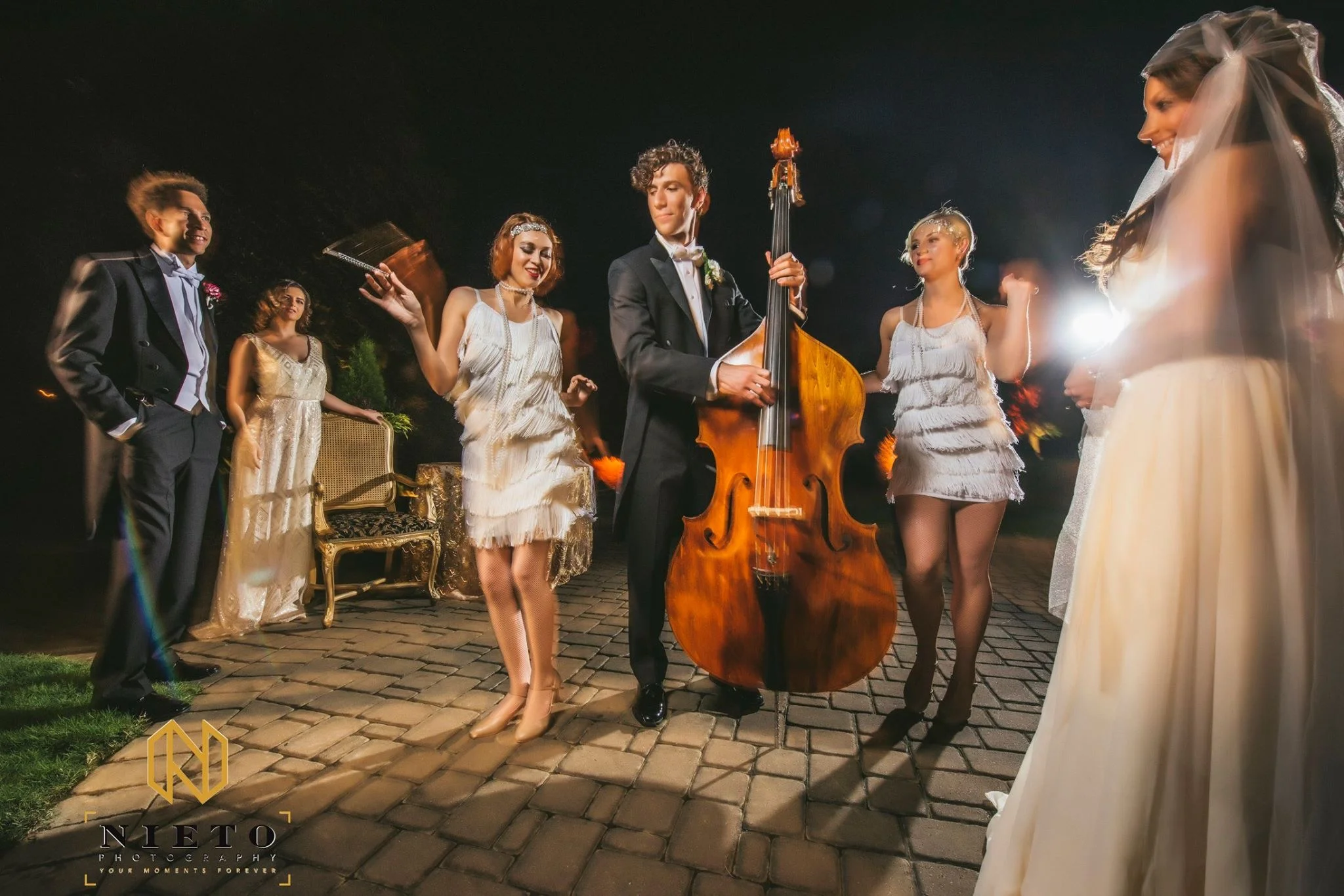 Flapper Dancers in White Costumes Interacting with Guests at Outdoor Event