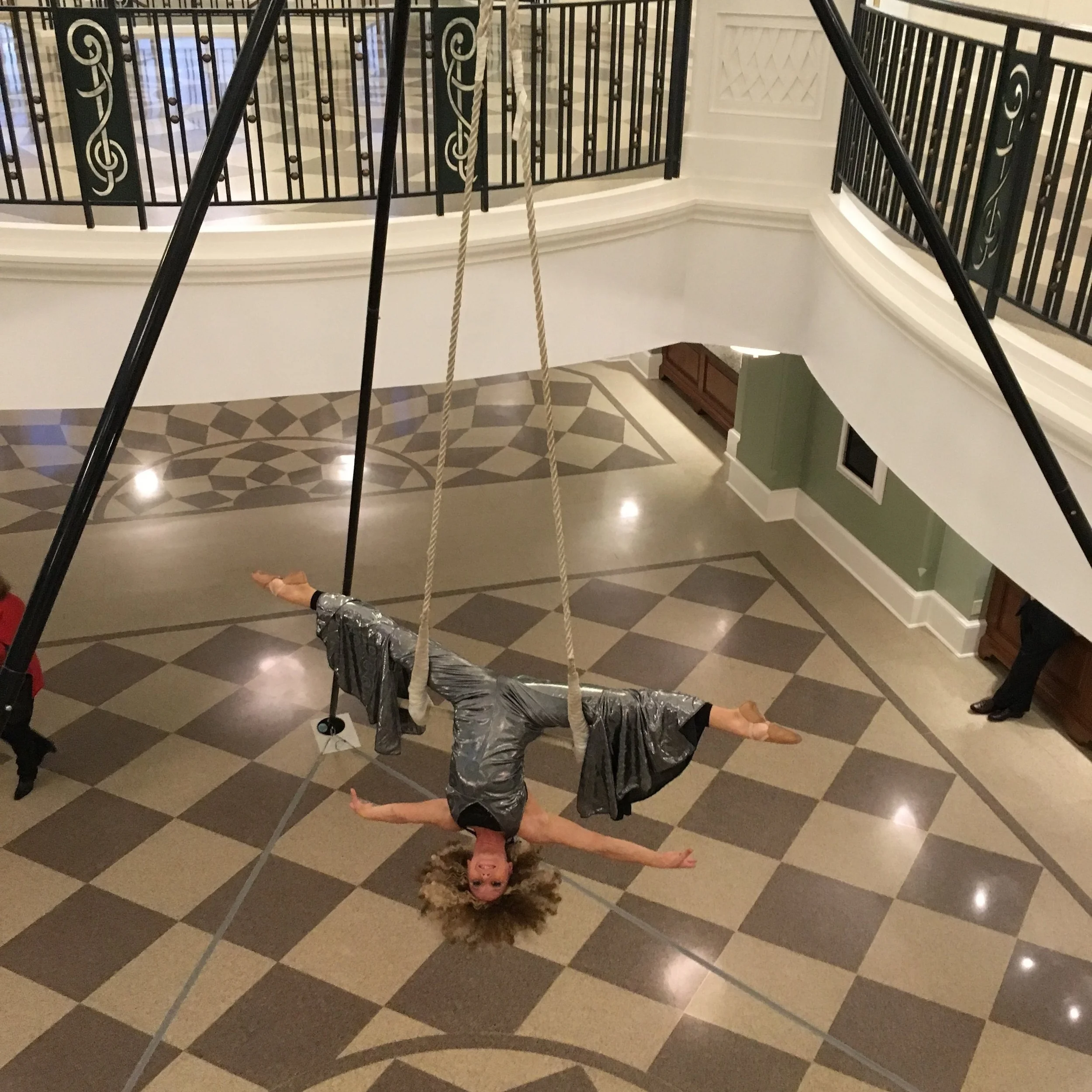 Aerialist performing on trapeze in a silver bell bottomed jumpsuit at a disco themed event