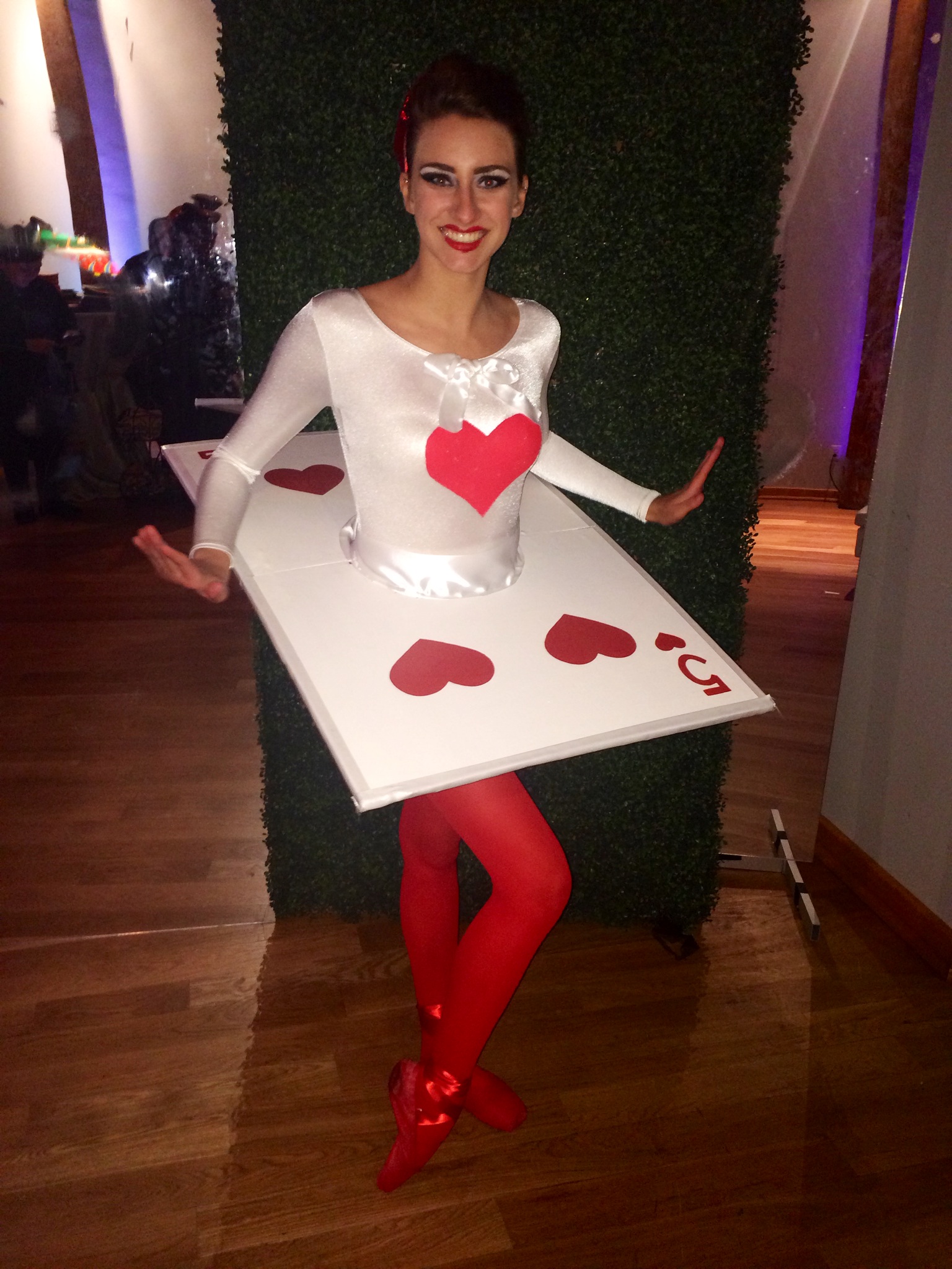 A performer in a five of hearts playing card costume for an Alice in Wonderland themed party