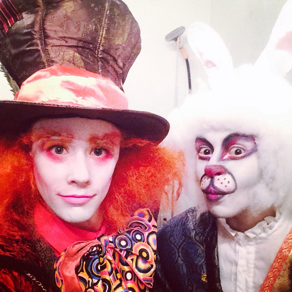 Two performers in Mad Hatter and White Rabbit inspired costumes for an Alice in Wonderland themed party