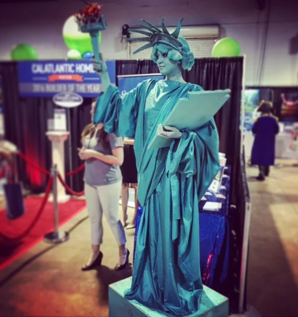 Statue of Liberty inspired living statue posing of a pedestal at a patriotic themed event in a convention center