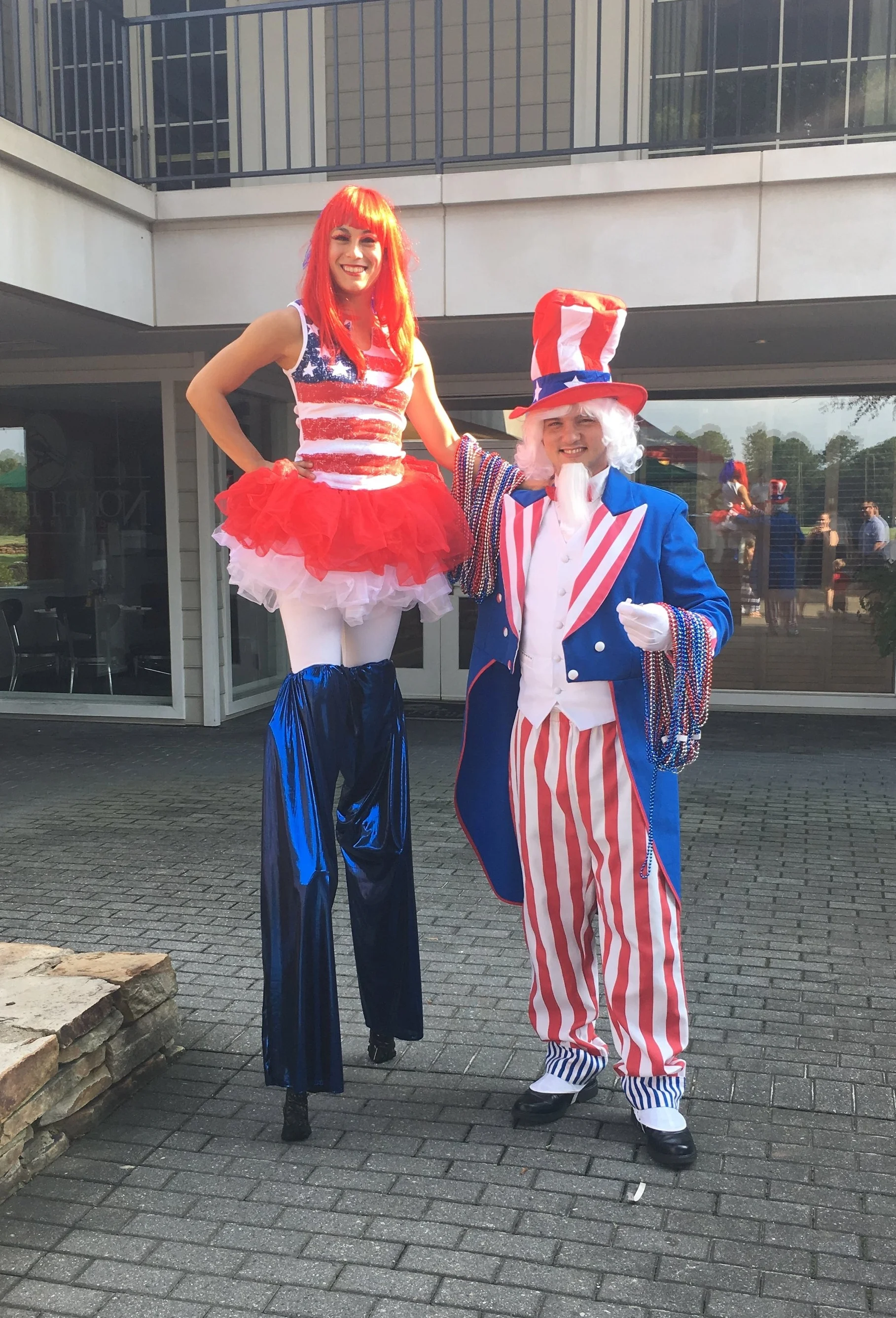 Uncle Sam costumed character and red, white and blue costumed stilt walker posing for a photo at a Patriotic themed event
