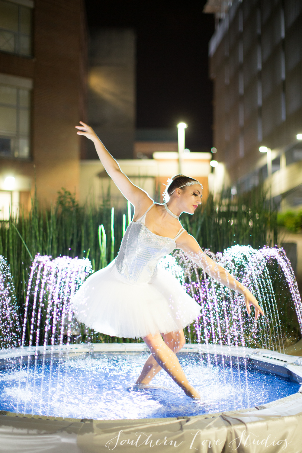 Ballerina in a white tutu dancing inside a fountain posed in a tondu front