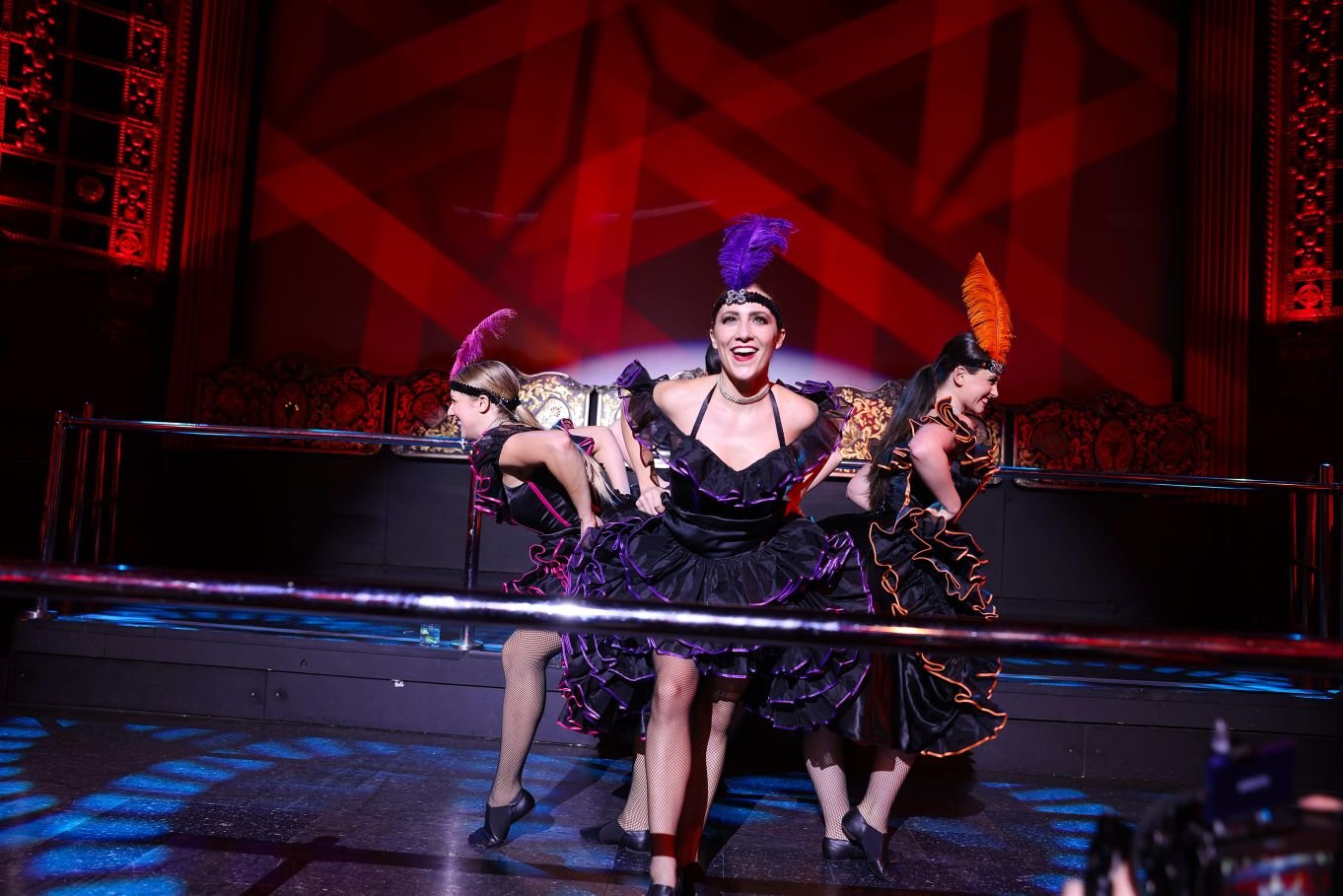 Can Can Dancers performing a choreographed routine in multicolored can can costumes and feather headpieces for a Moulin Rouge themed dinner theater event in Houston, Texas
