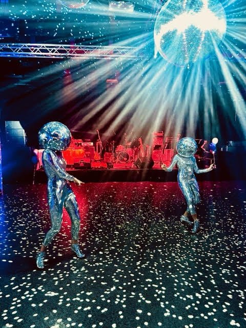 Two living Disco Ball performers dancing under a disco ball on the dance floor
