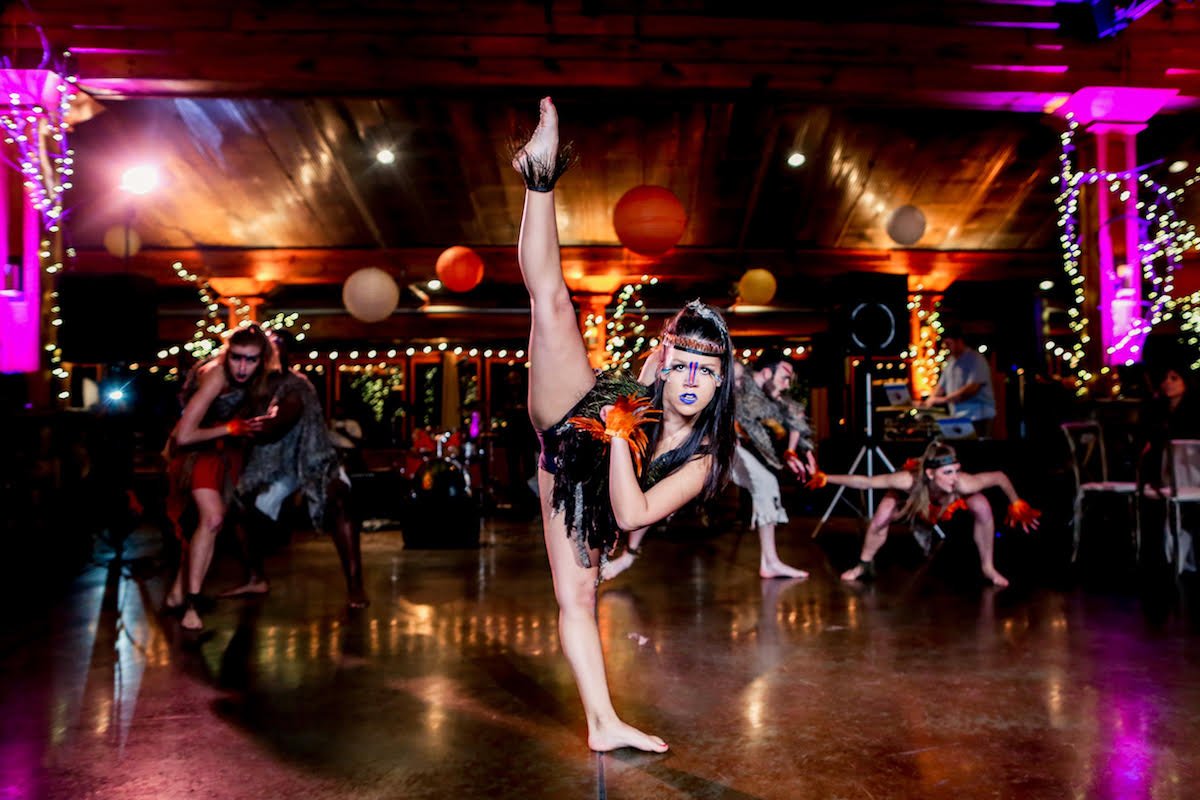 Choreographed dance routine for a jungle themed event, dancer in the front of the shot posed in a tilt battement