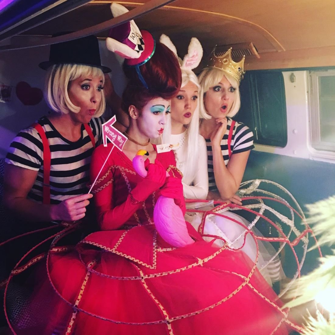 Four performers in Red Queen, White Rabbit, and Tweedle Dees inspired costumes for an Alice in Wonderland themed party