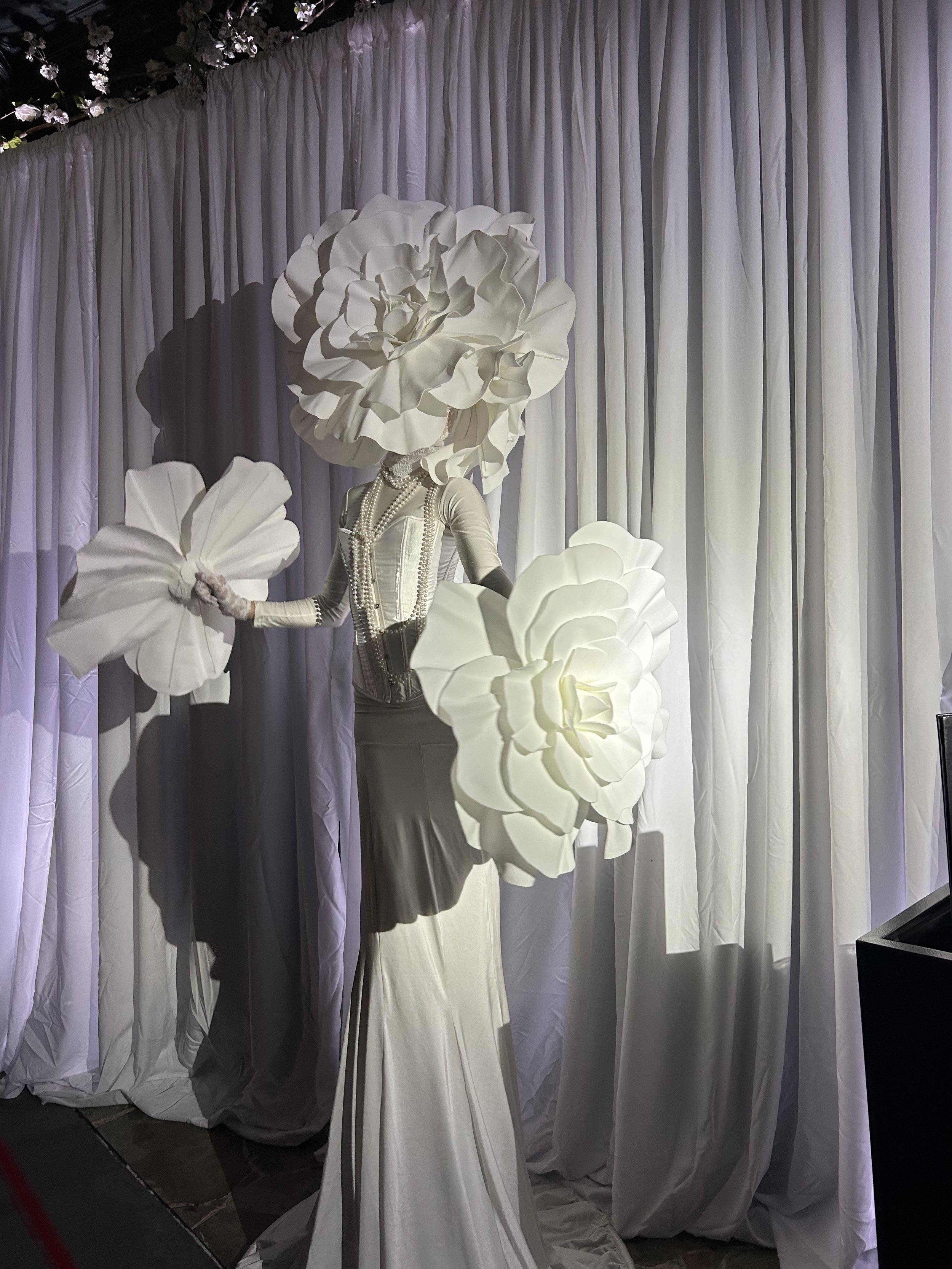 Living Centerpiece costumed in all white with huge white floral headpiece at an event in Charleston