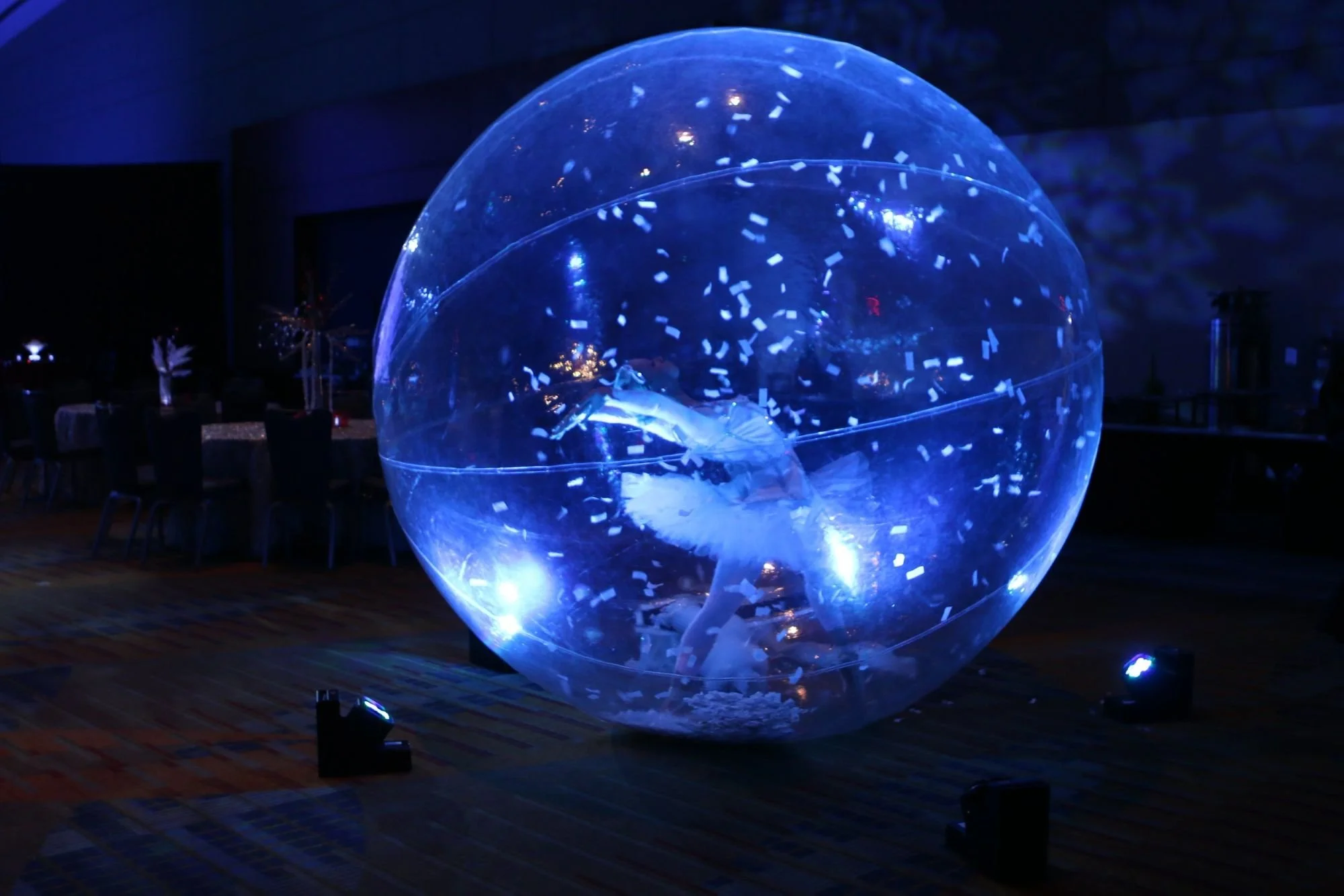 Life-sized snow globe with white snow confetti and ballerina performer inside costumed in a white tutu
