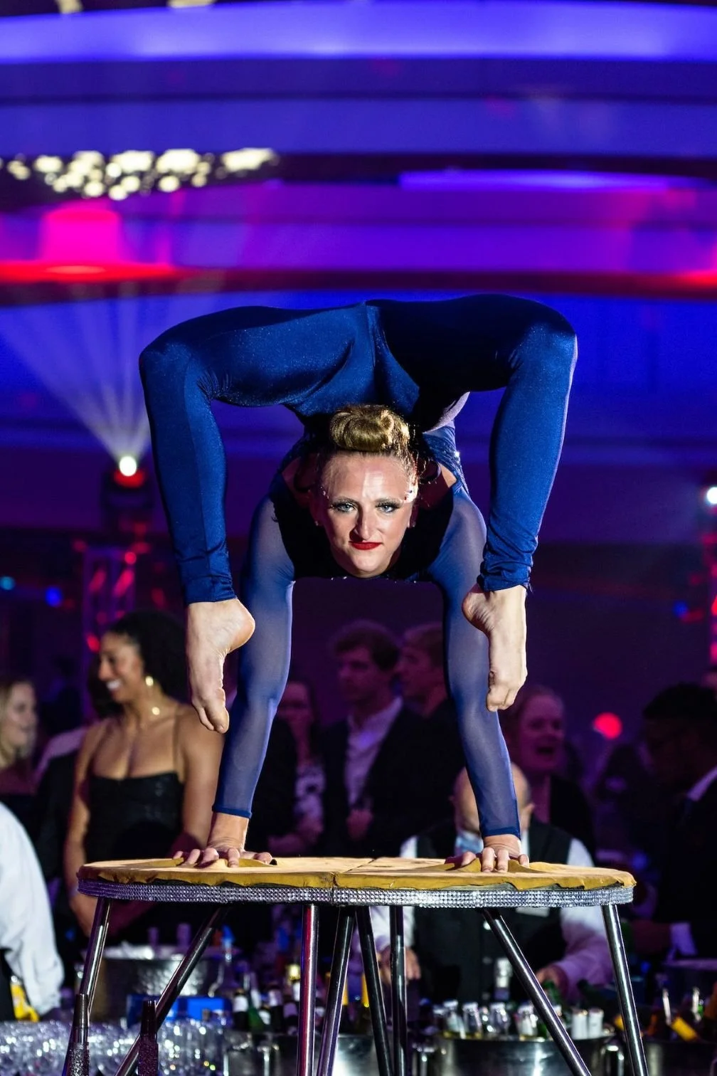 Contortionist Performing Handstand on Table in Blue-Purple Costume