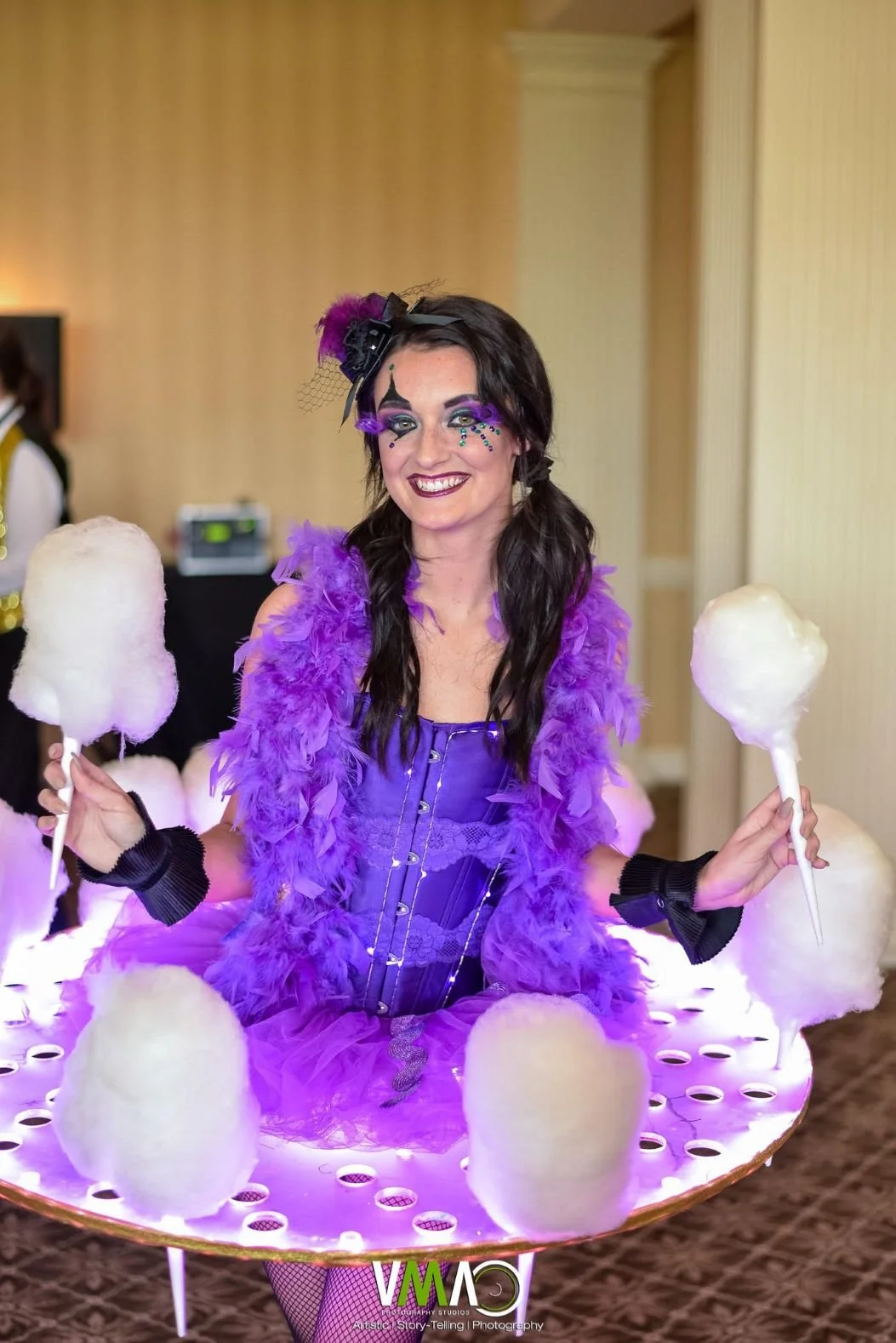 Performer with a table around her waist and inserts for cotton candy in the table dressed in a purple costume for a circus themed event