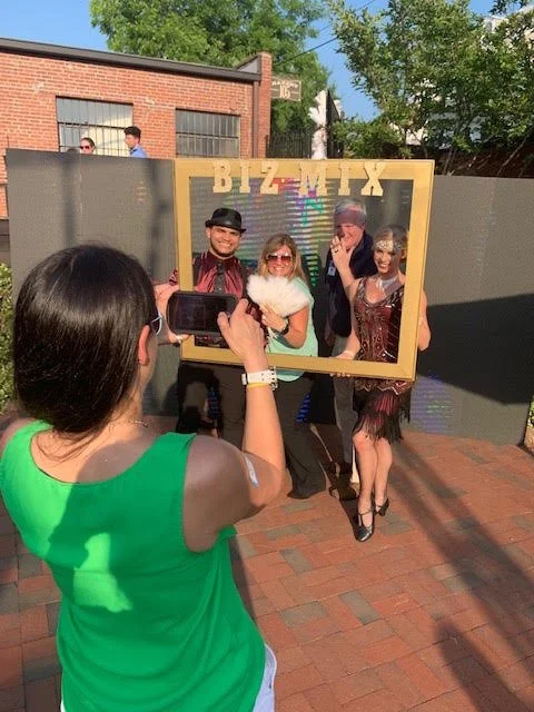 Gatsby Maroon Duo Pose with Guests and BIZ MIX Frame at Outdoor Party