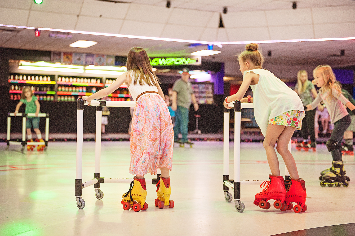  group of children roller skating and rollerblading, some with roller skate trainers  