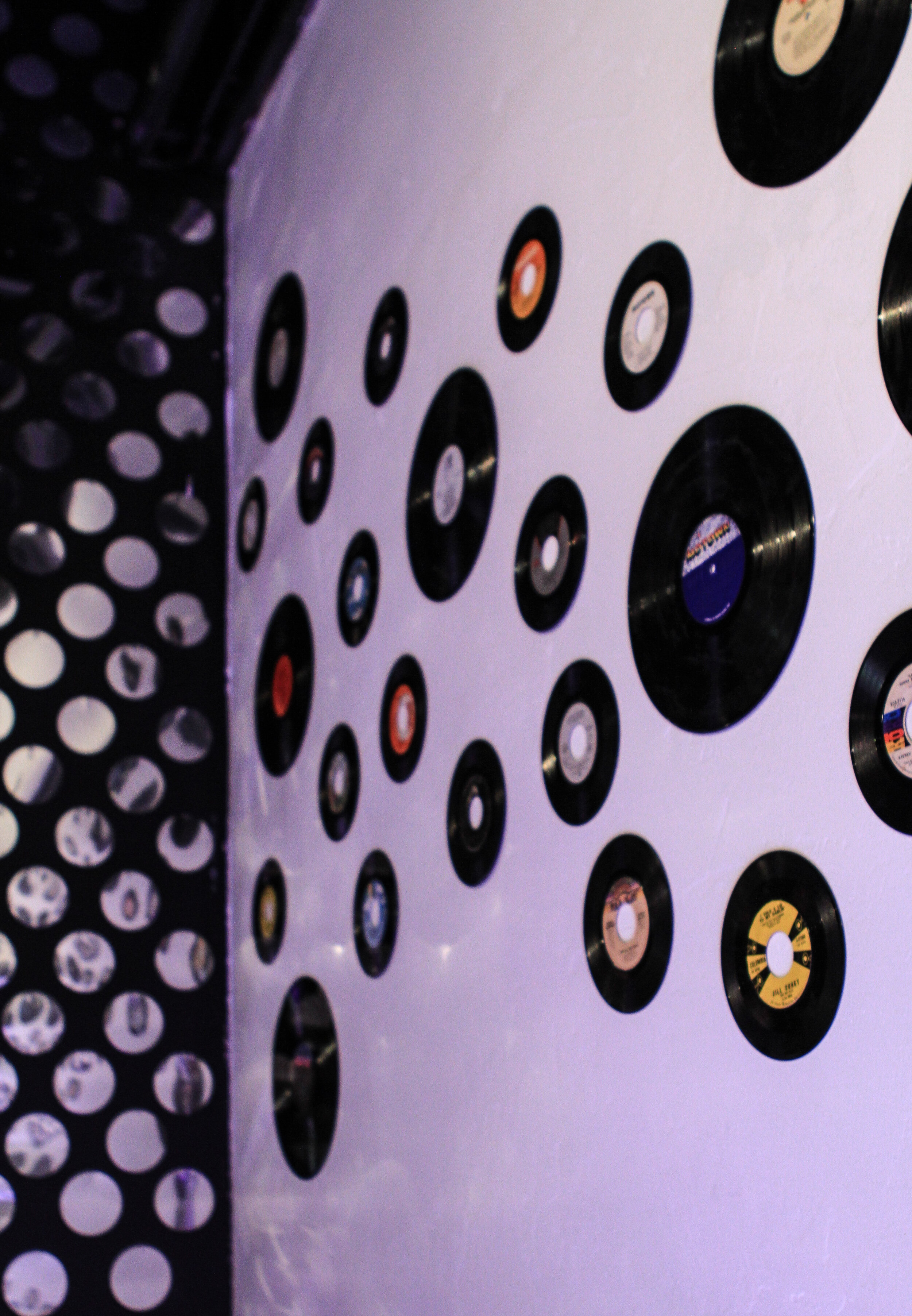  vinyl records hanging on a wall with reflected light from a disco wall 