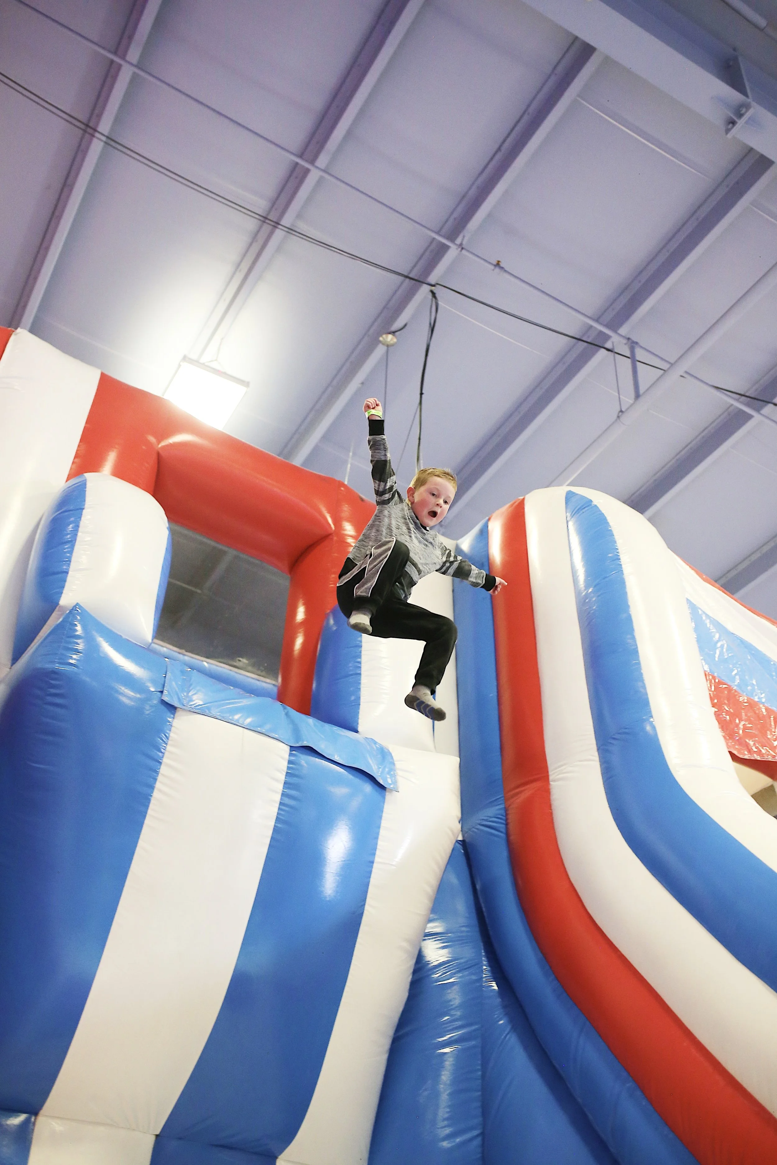  boy jumping off of overhang in a bouncy house  