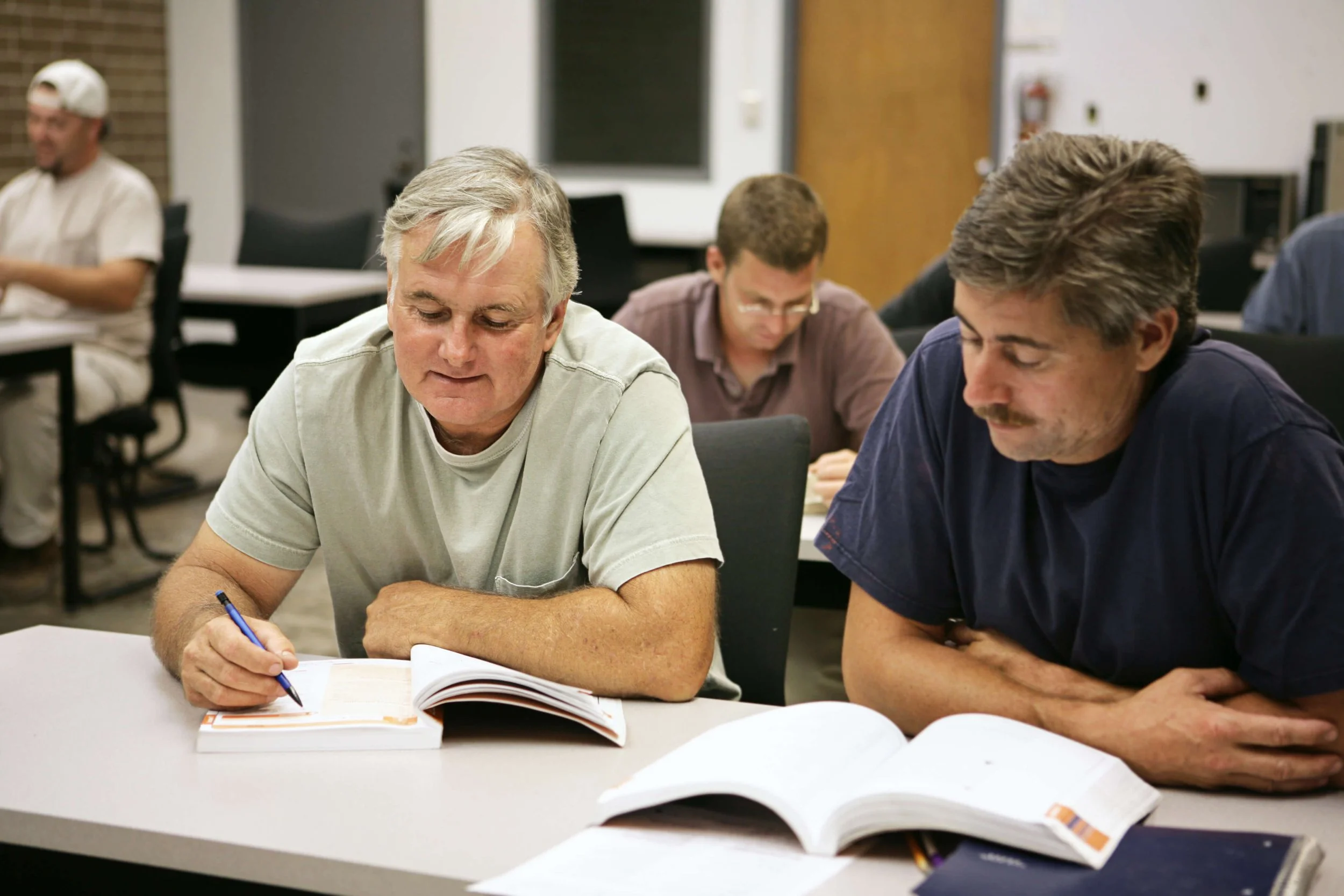 Two older men studying textbooks in a training class.