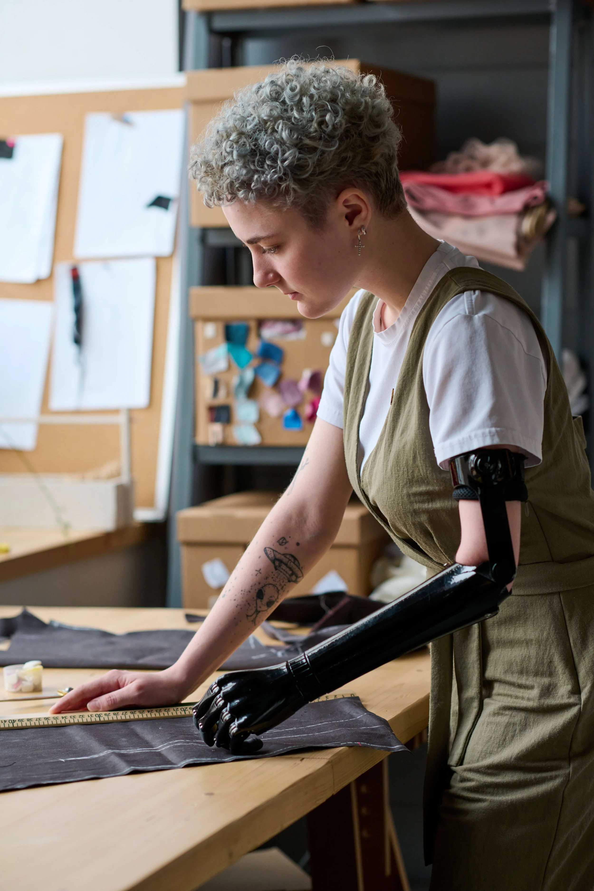 A woman with a prosthetic arm works in a fabric design studio.