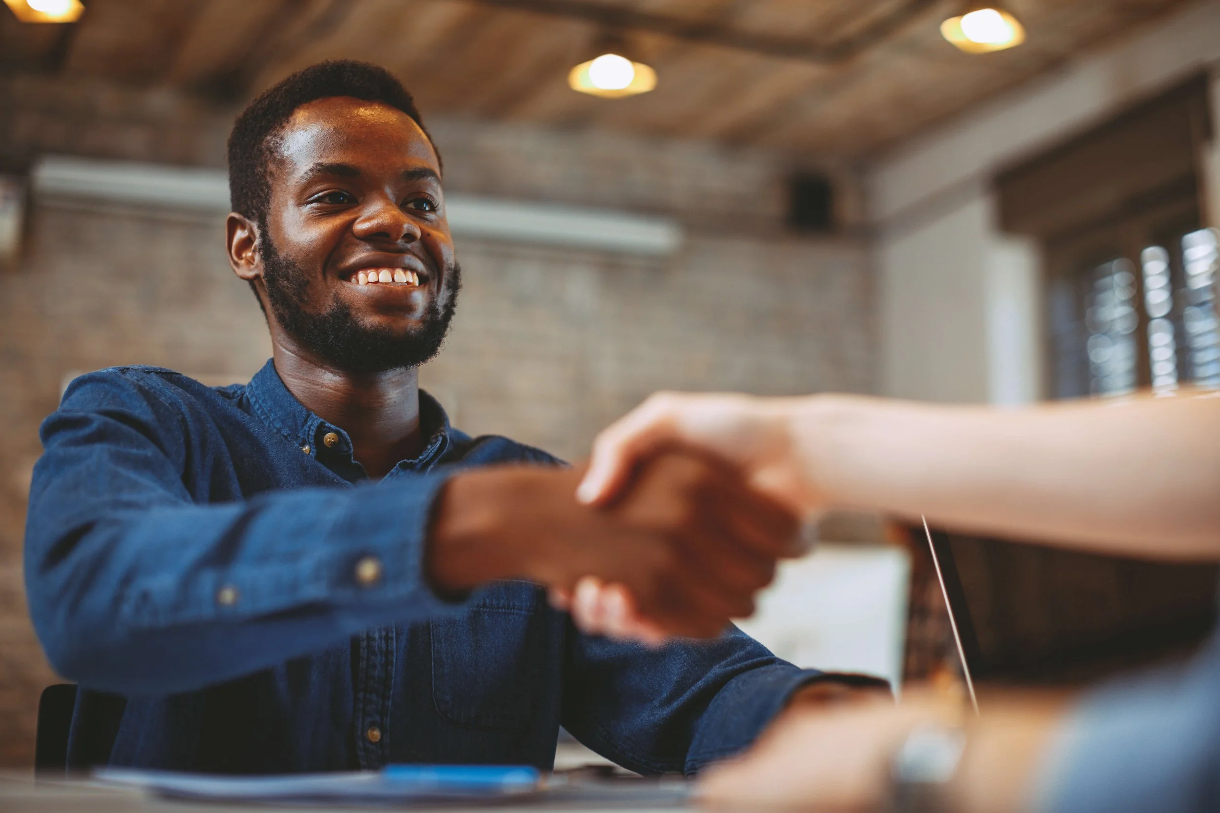 A young man shaking hands at an interview.