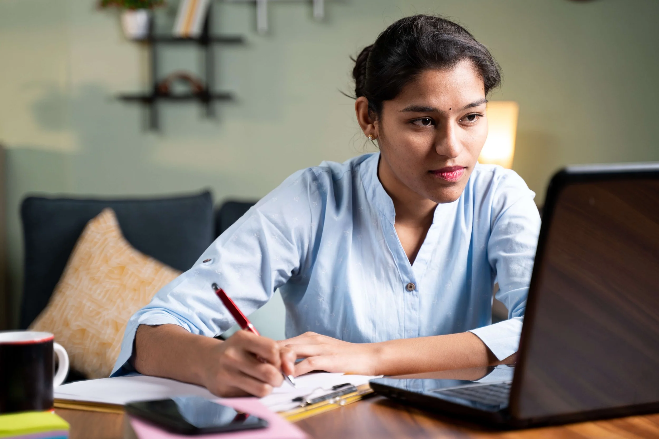 A young woman taking notes in an online workshop.