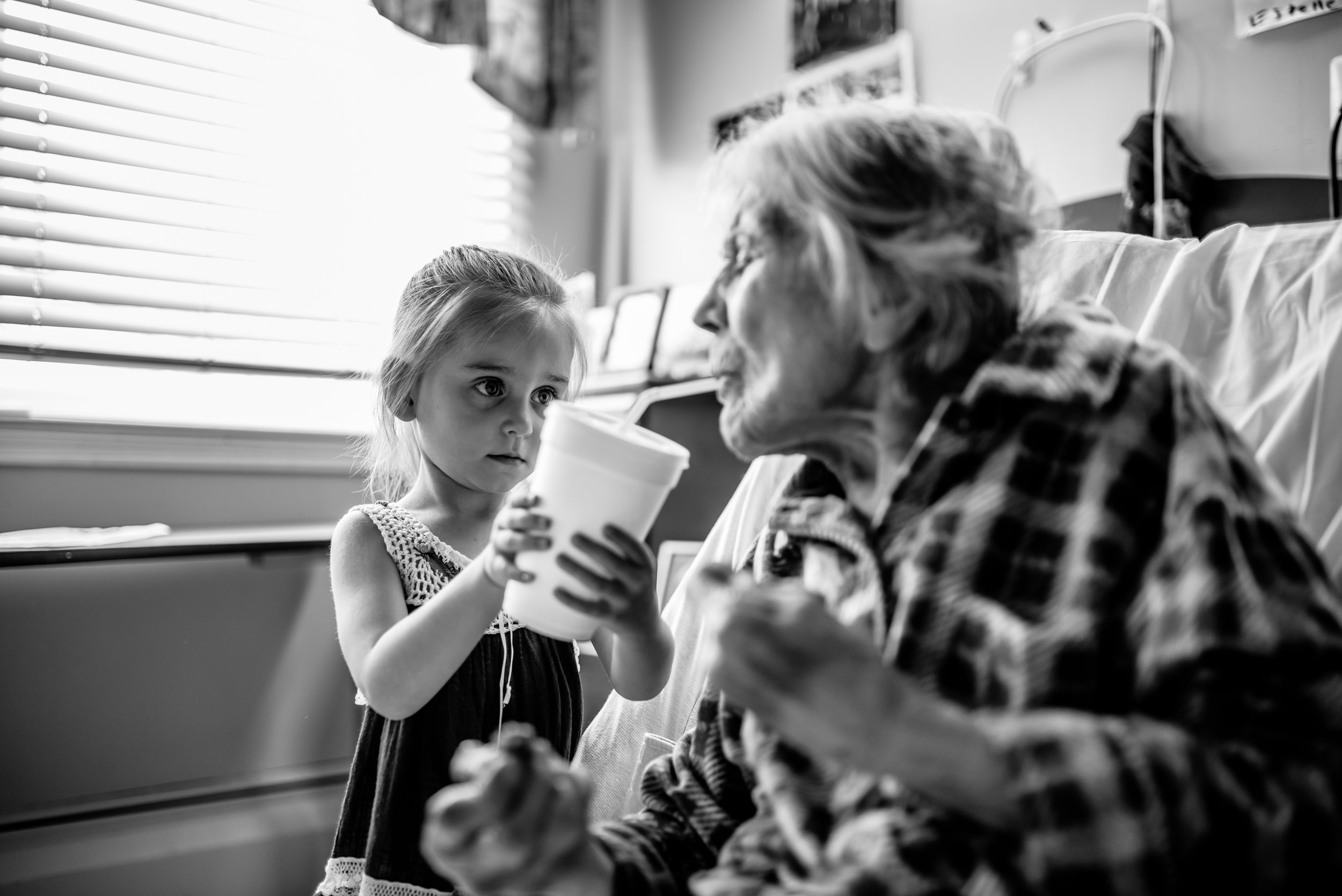 Girl helps great-great-grandmother drink from straw