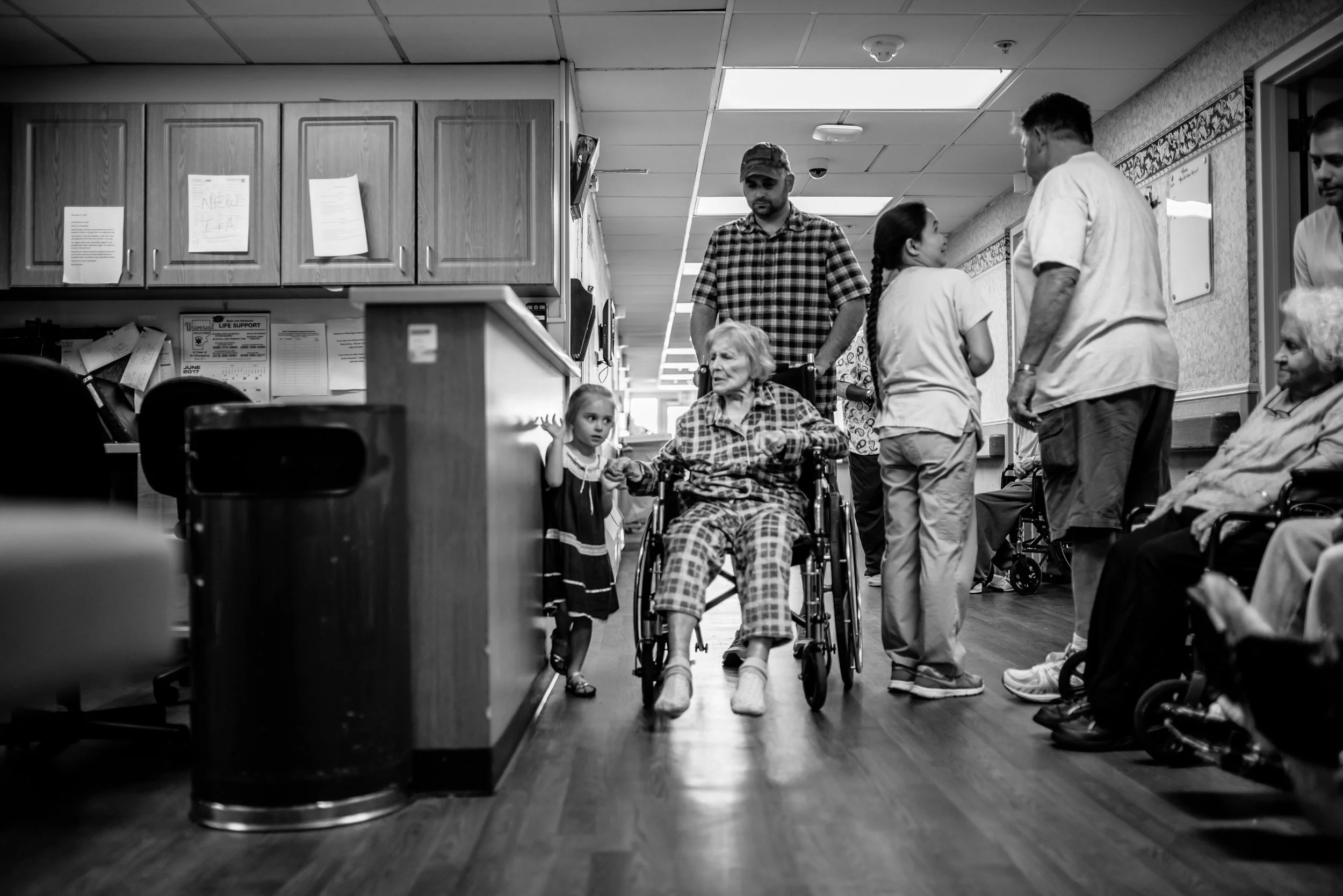 Man pushes great-great-grandmother in wheelchair and little girl walks beside them