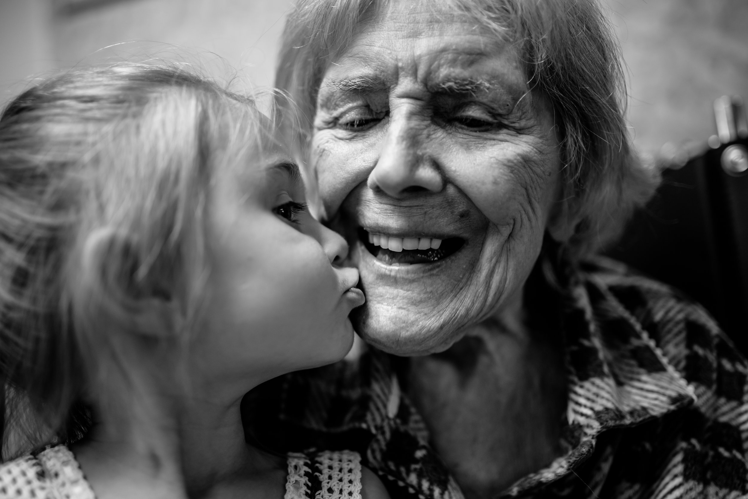 girl kisses great-great-grandmother who smiles