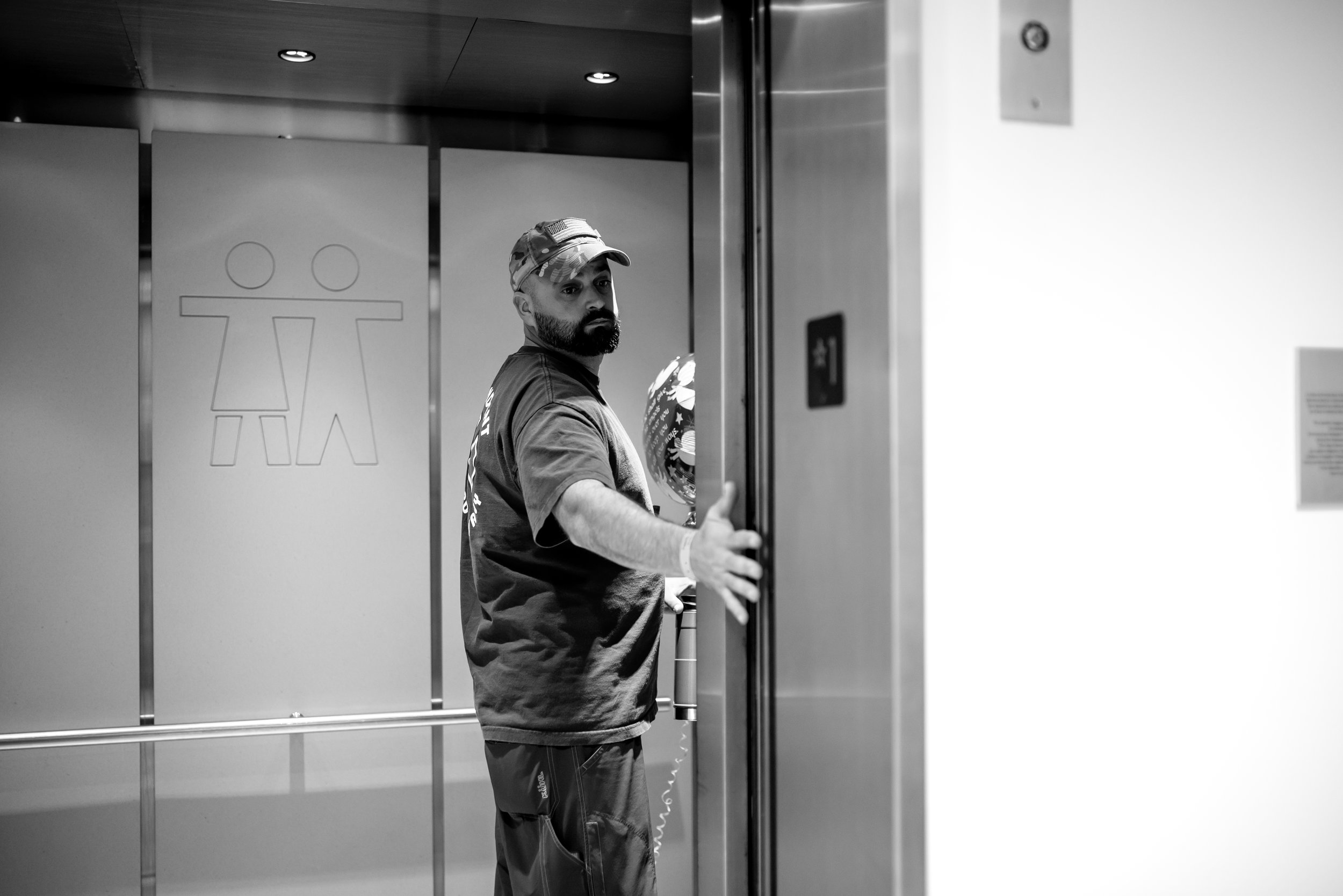 Husband holds hospital elevator door open for wife