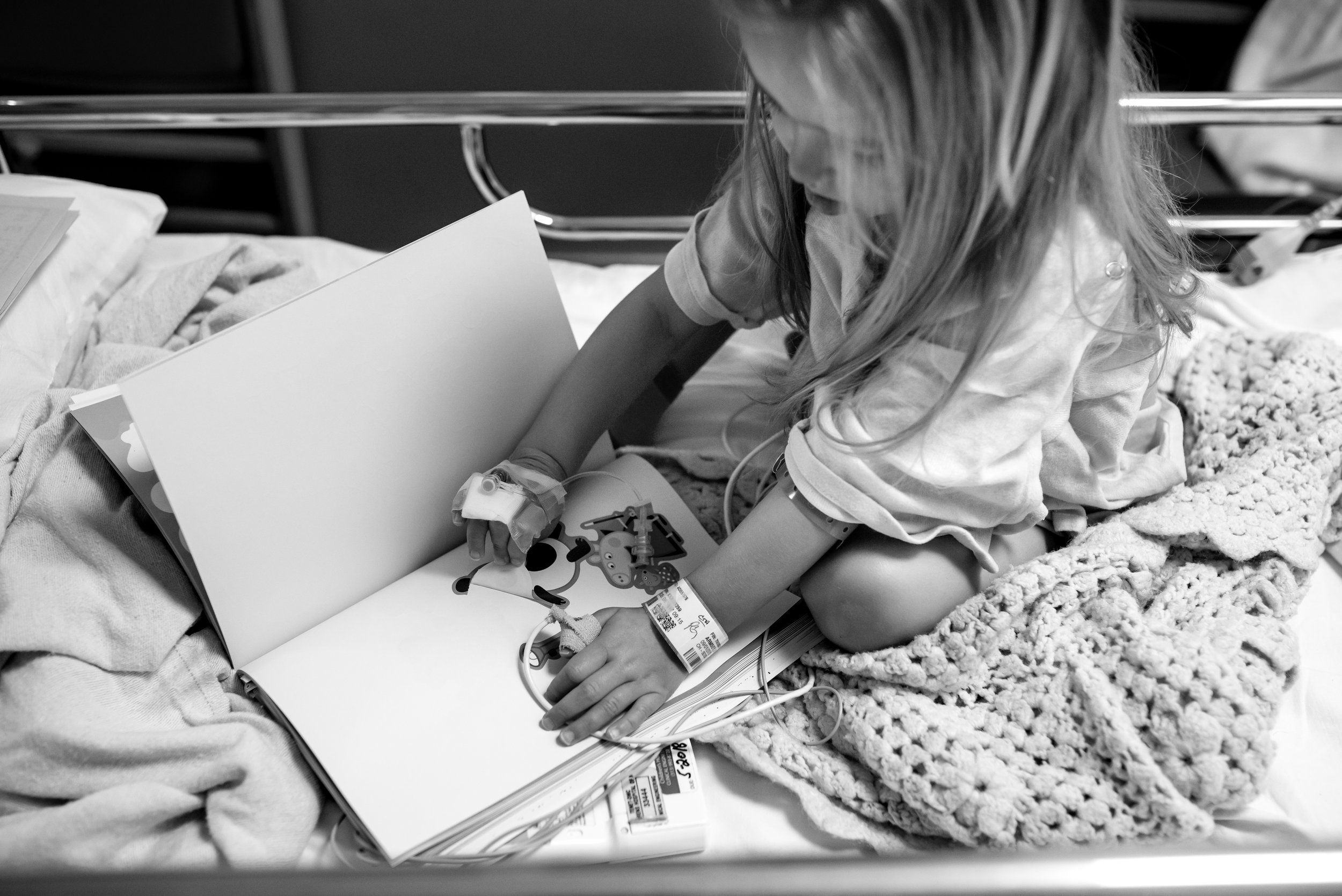 Girl plays with sticker book in observation unit at children's hospital
