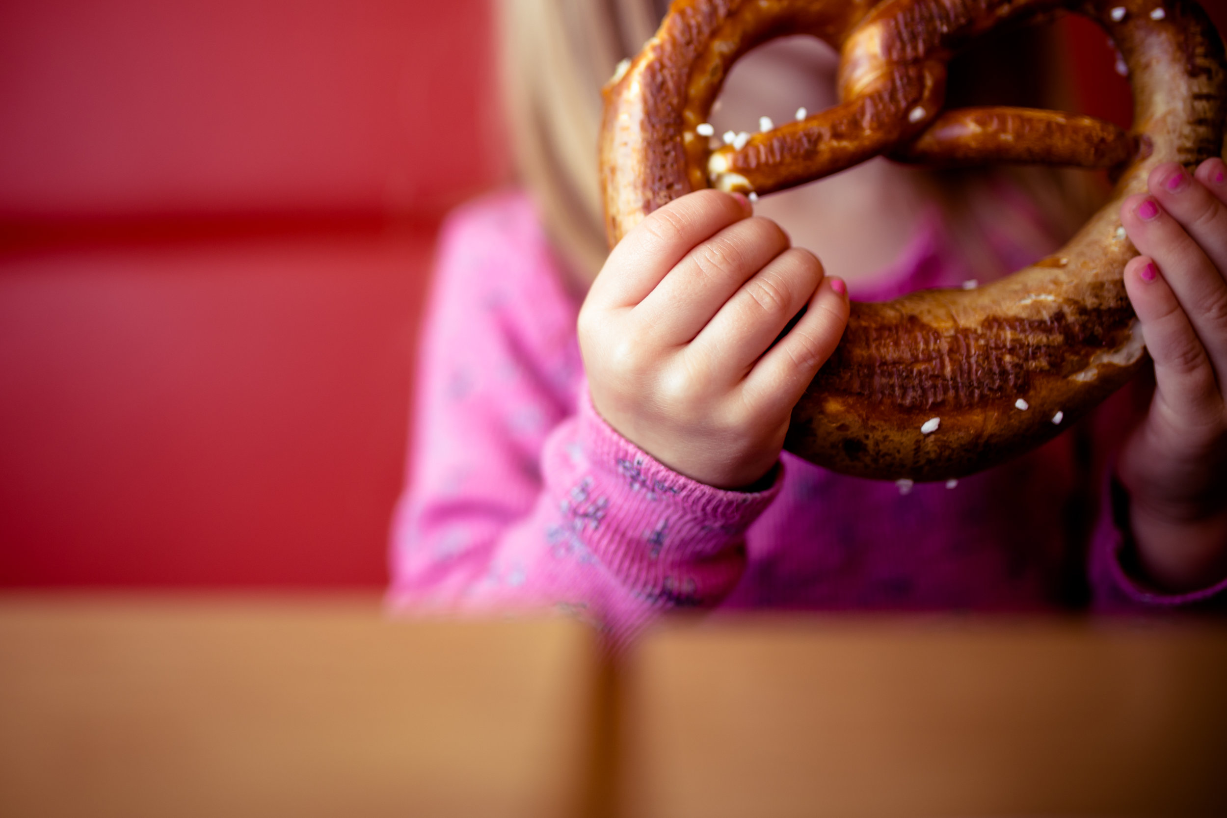 girl holds salted pretzel at bakery table