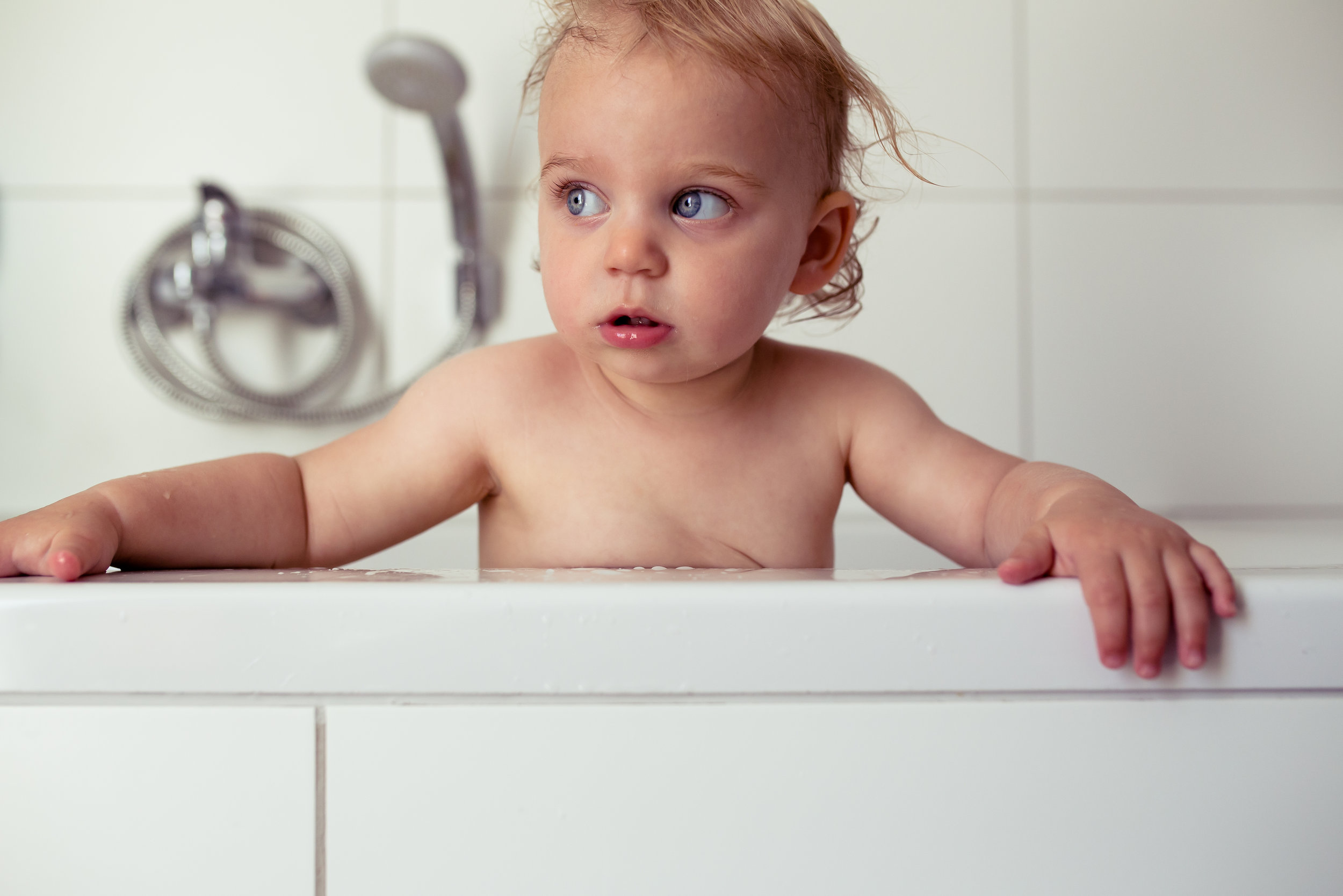 Baby looks intently to the distance while in bath tub