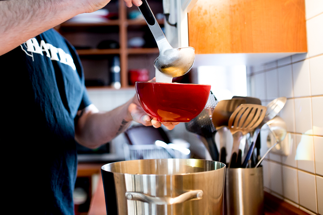 Man puts soup into bowl with ladel