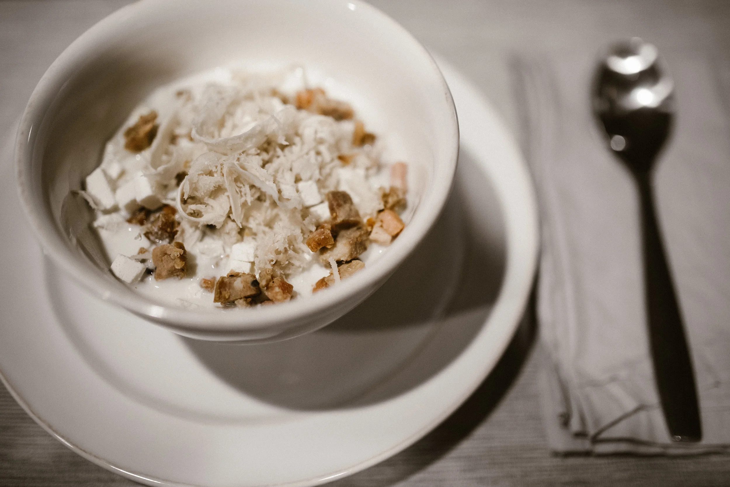 Zurek soup in a white bowl with a spoon beside it