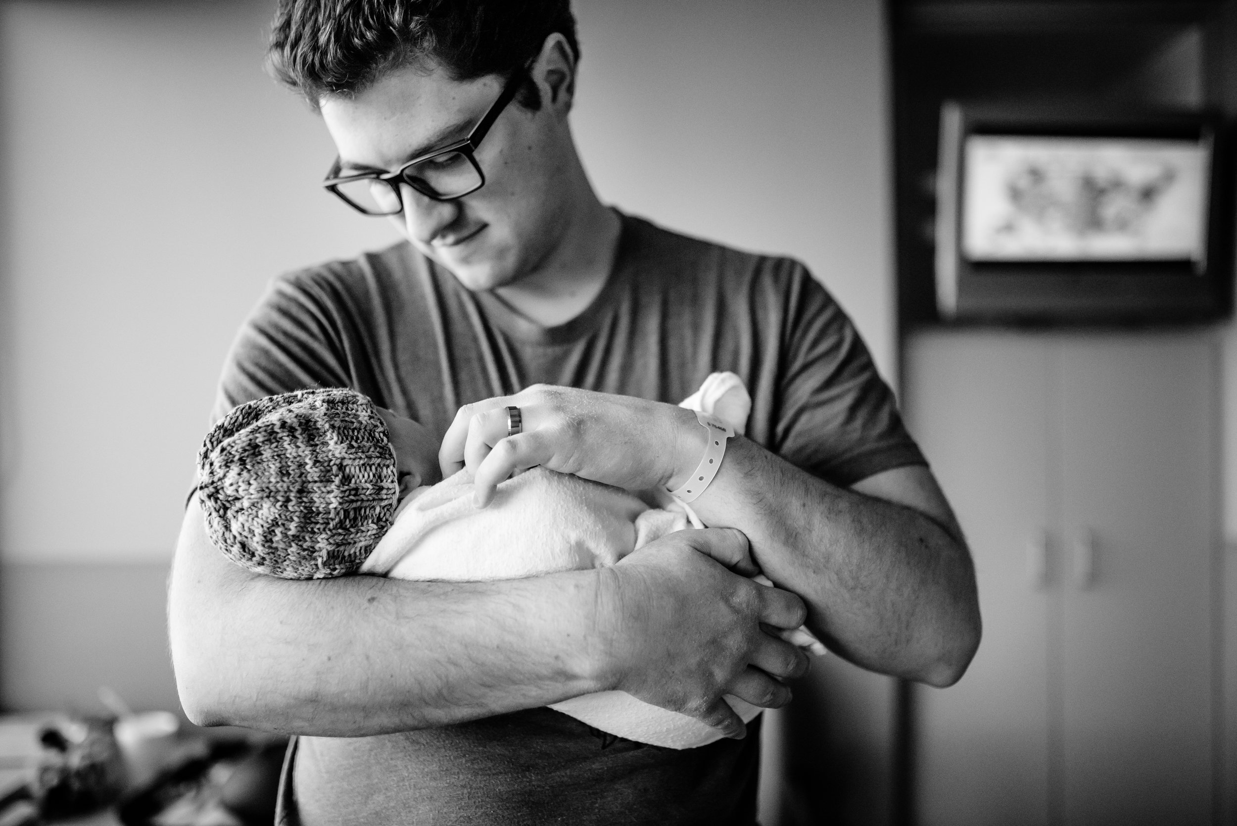 Dad holds swaddled newborn in hospital room