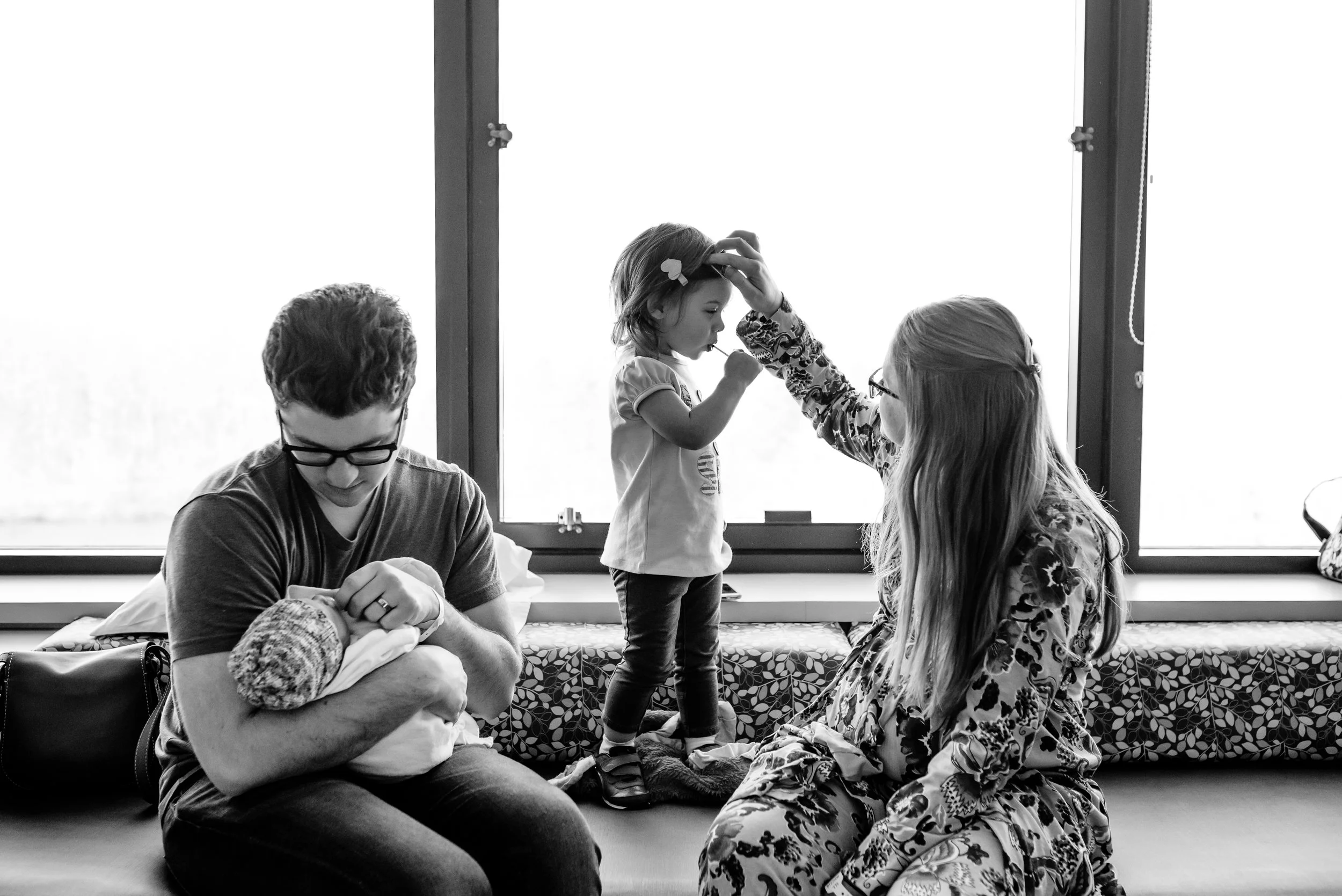Mom fixes daughter's hair while Dad holds newborn son.