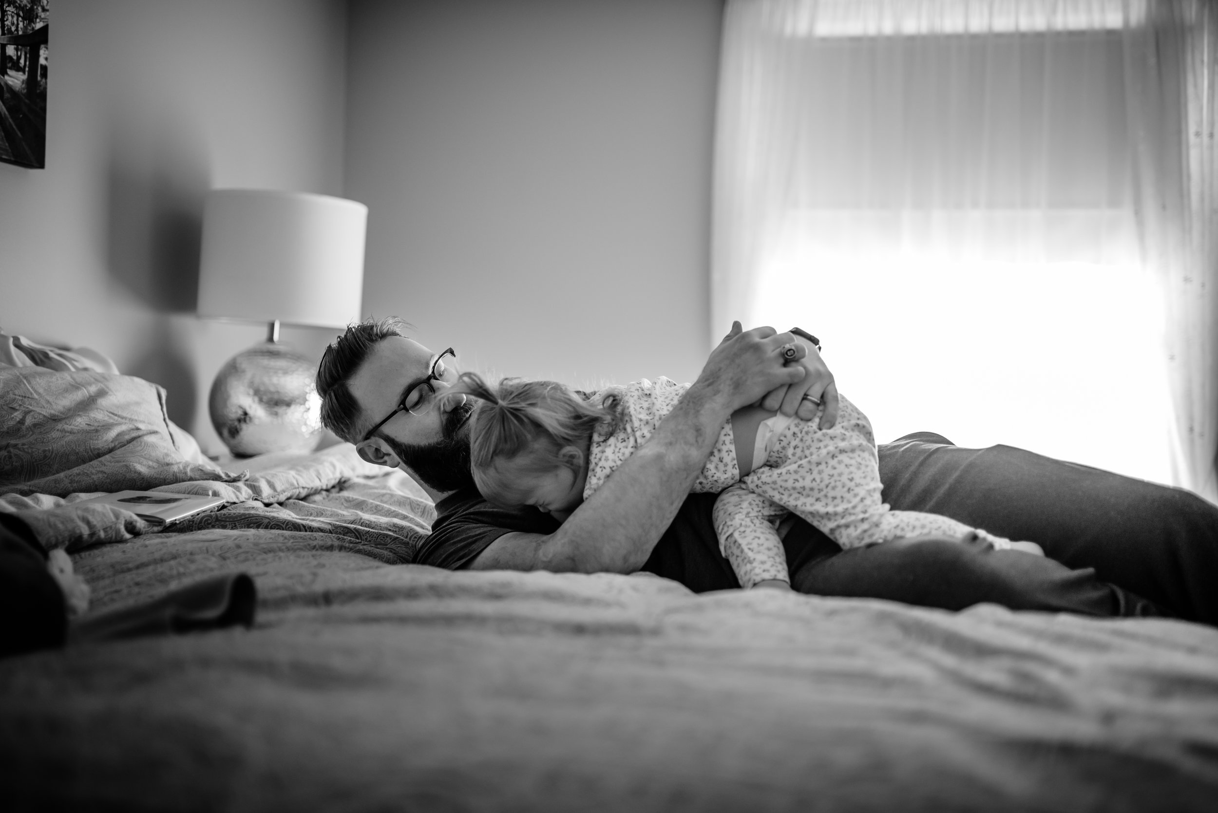 Dad hugs daughter atop bed