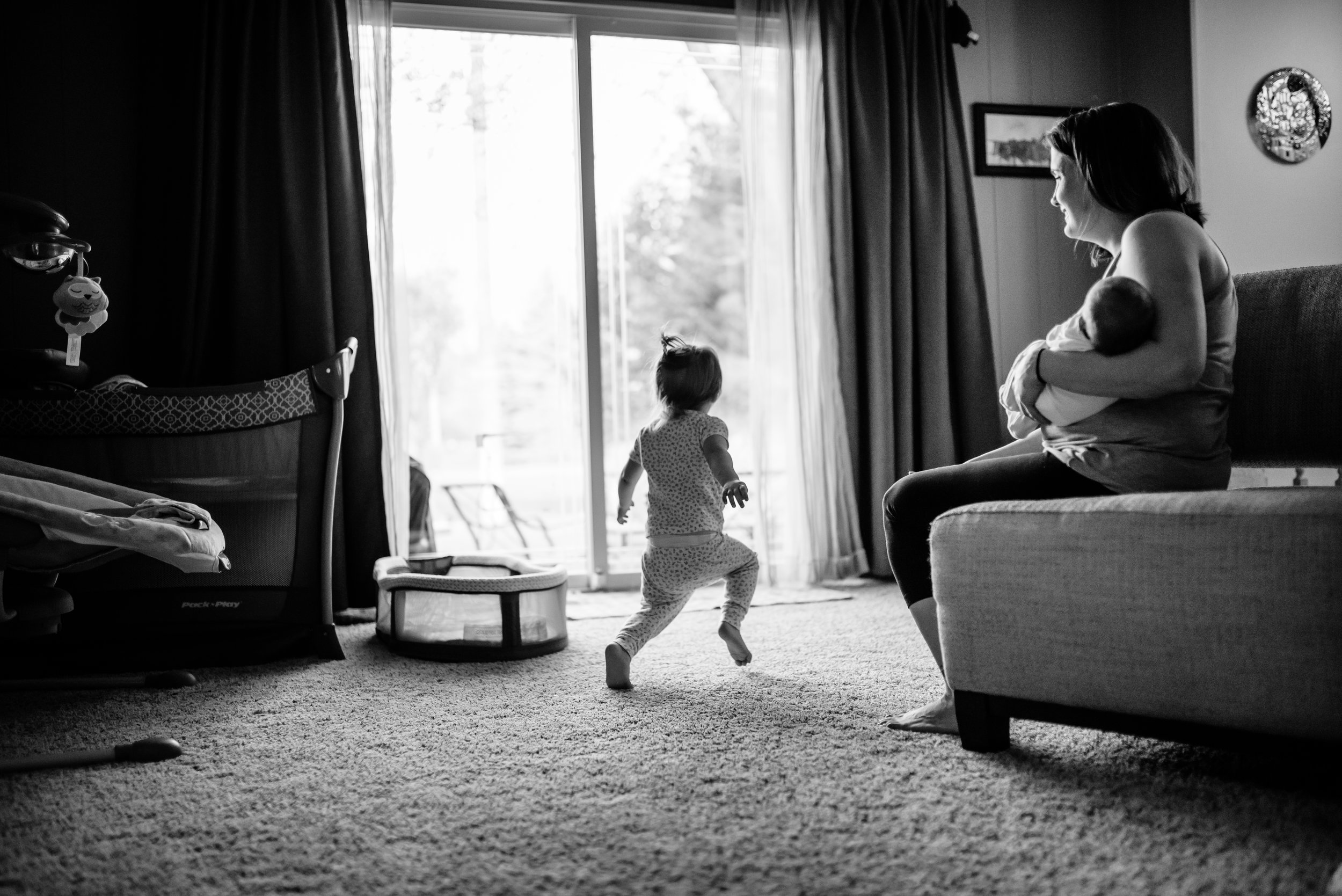 Mom holds baby and watches daughter dance