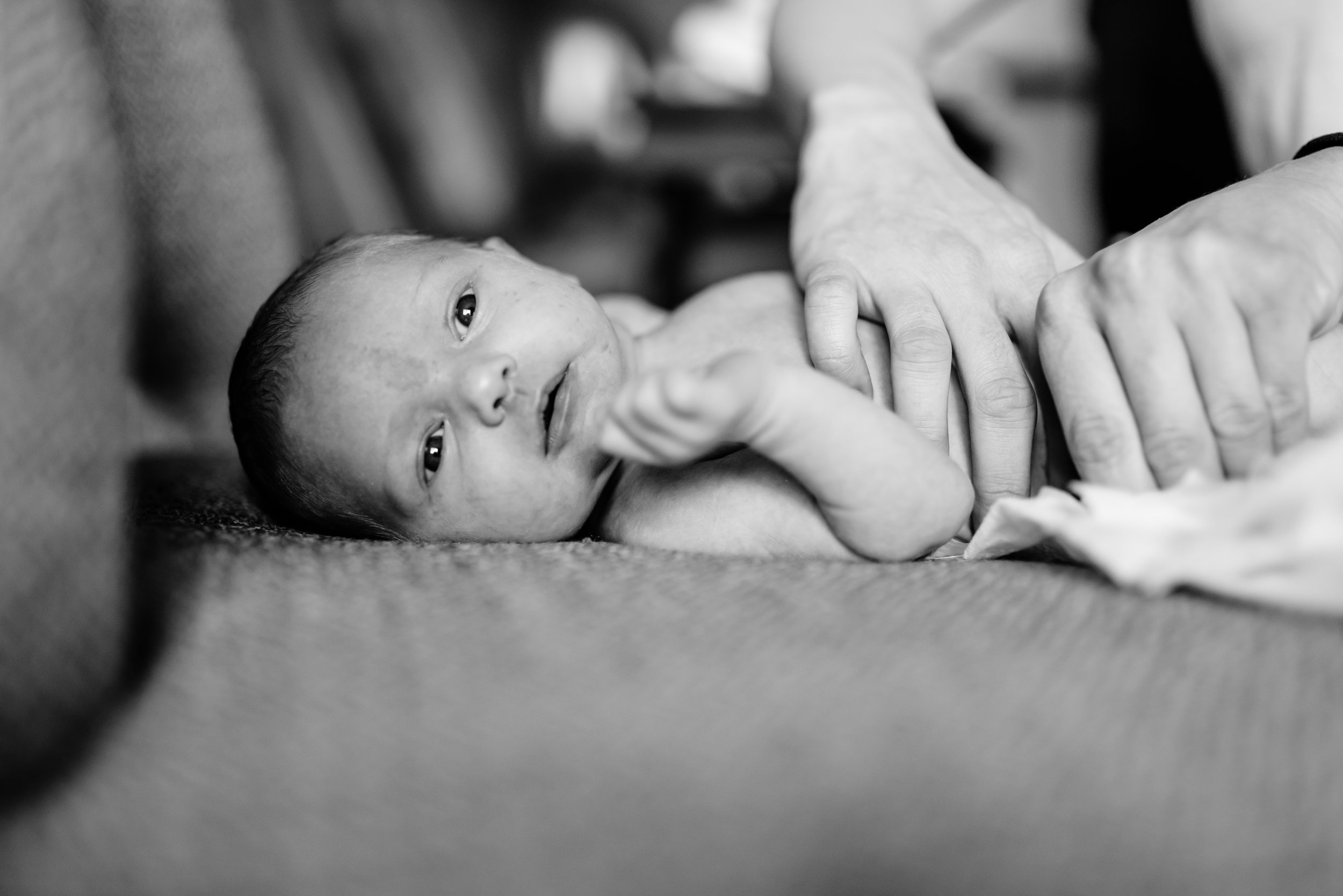 Newborn lies on chair while being dressed