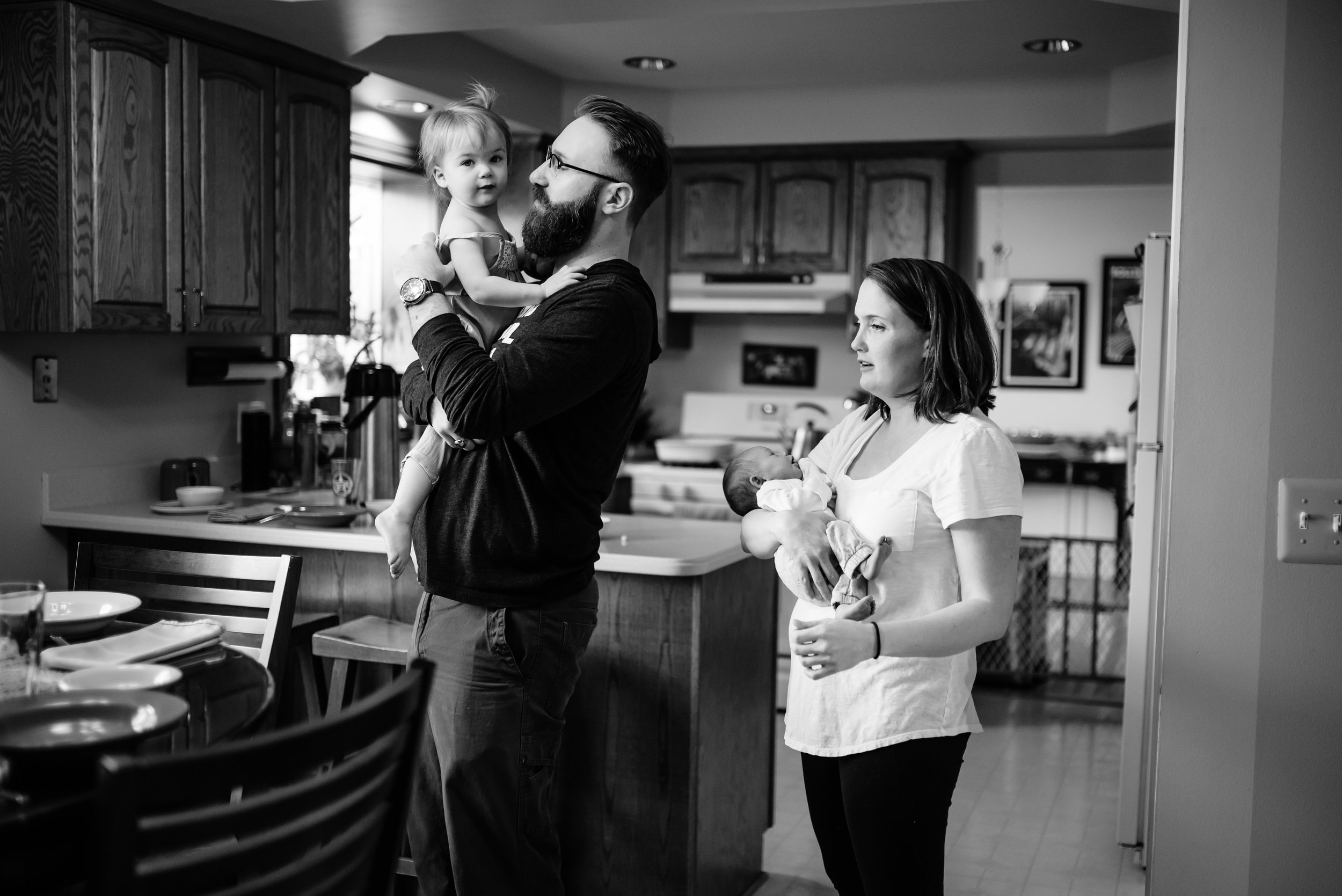 Mom and Dad hold children in kitchen