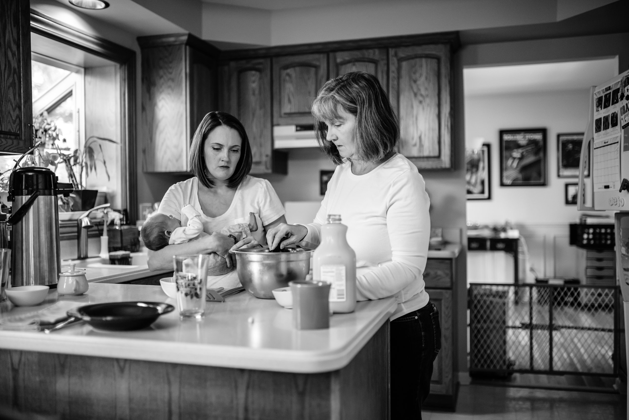 Mom holds baby as she preps breakfast with Grandma